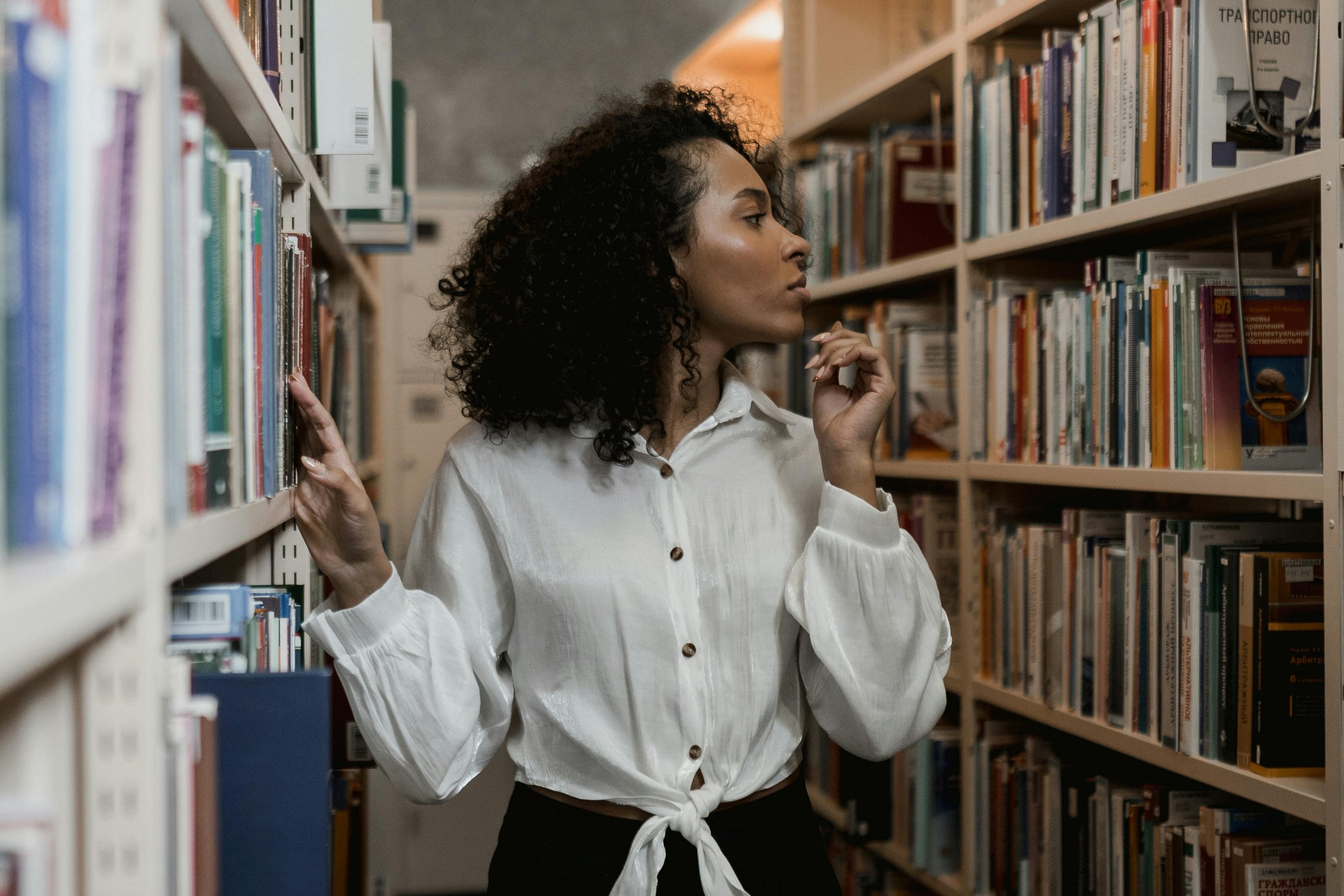 woman with curly hair browsing the selfdiscovery books at the library