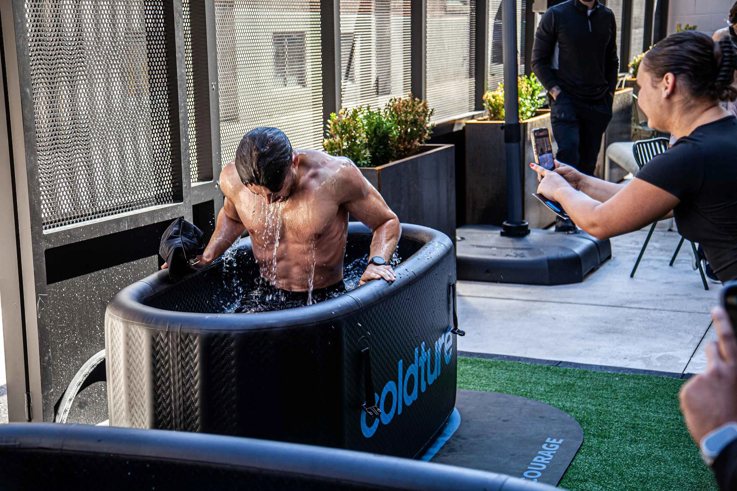 Person using a cold plunge tub for recovery after training at a wellness facility.