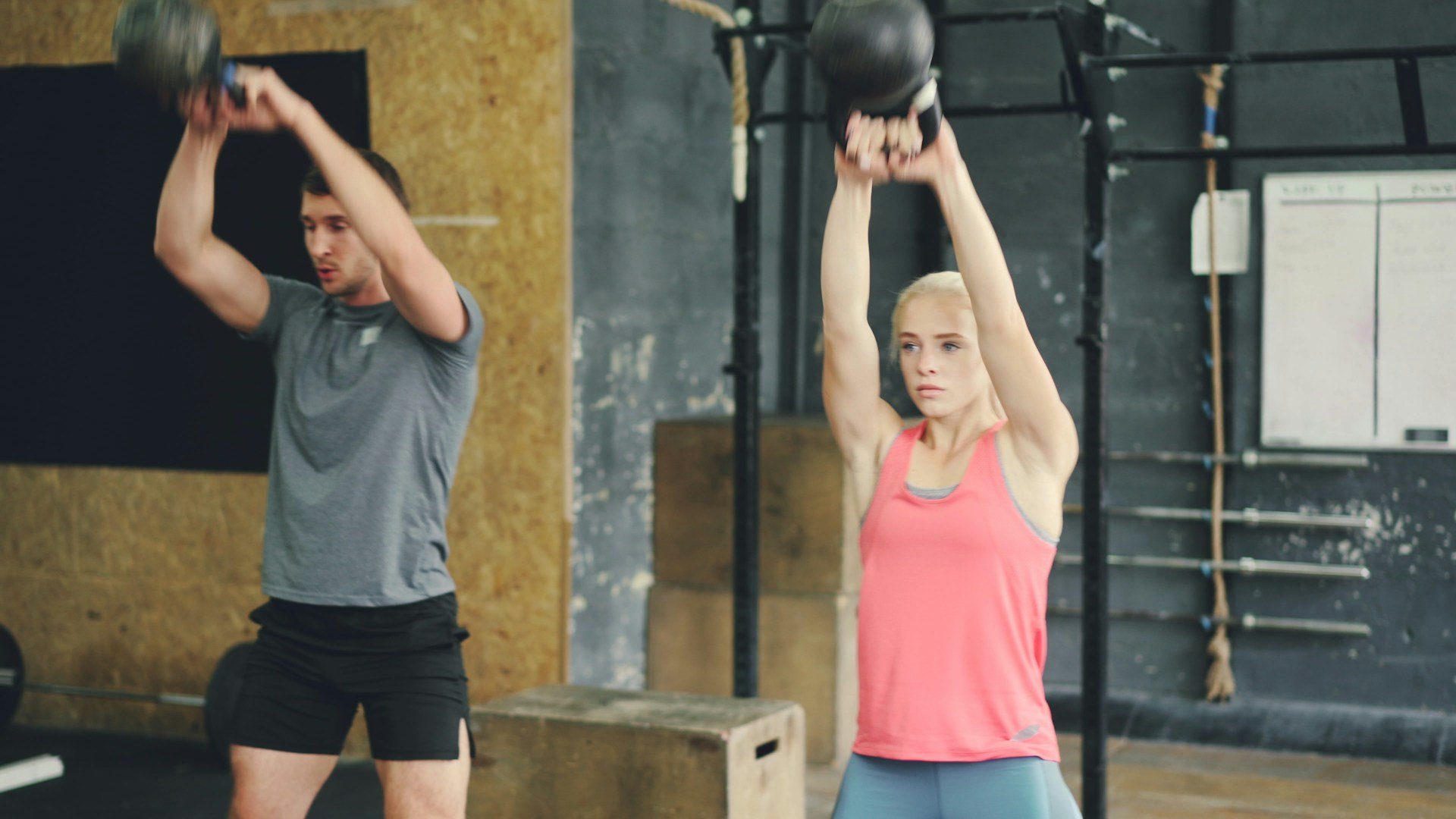 Two people performing kettlebell swings in a gym, highlighting functional training, hip power and full-body conditioning.