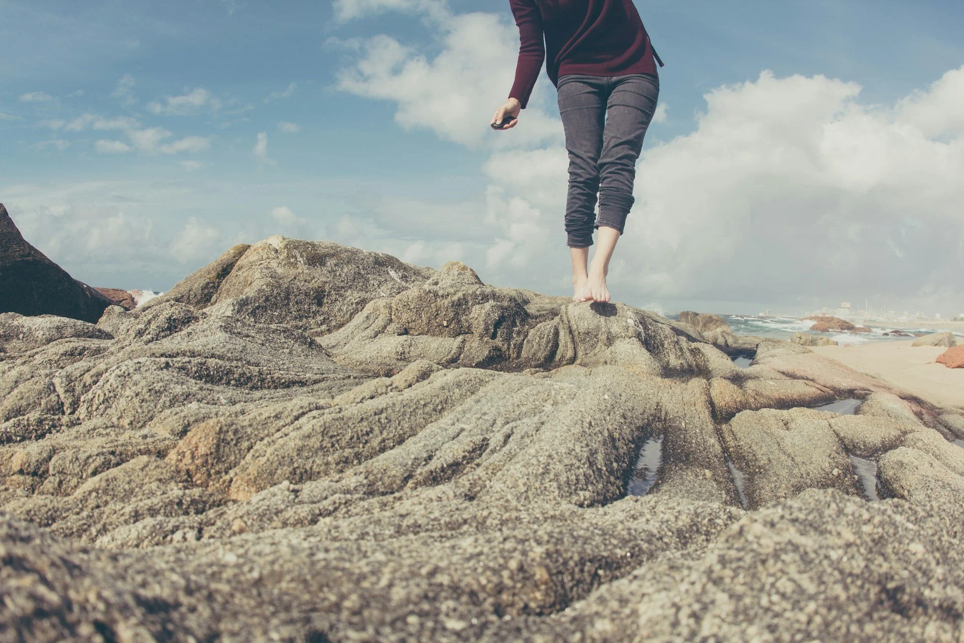 Person walking barefoot across coastal rocks for balance and mobility.