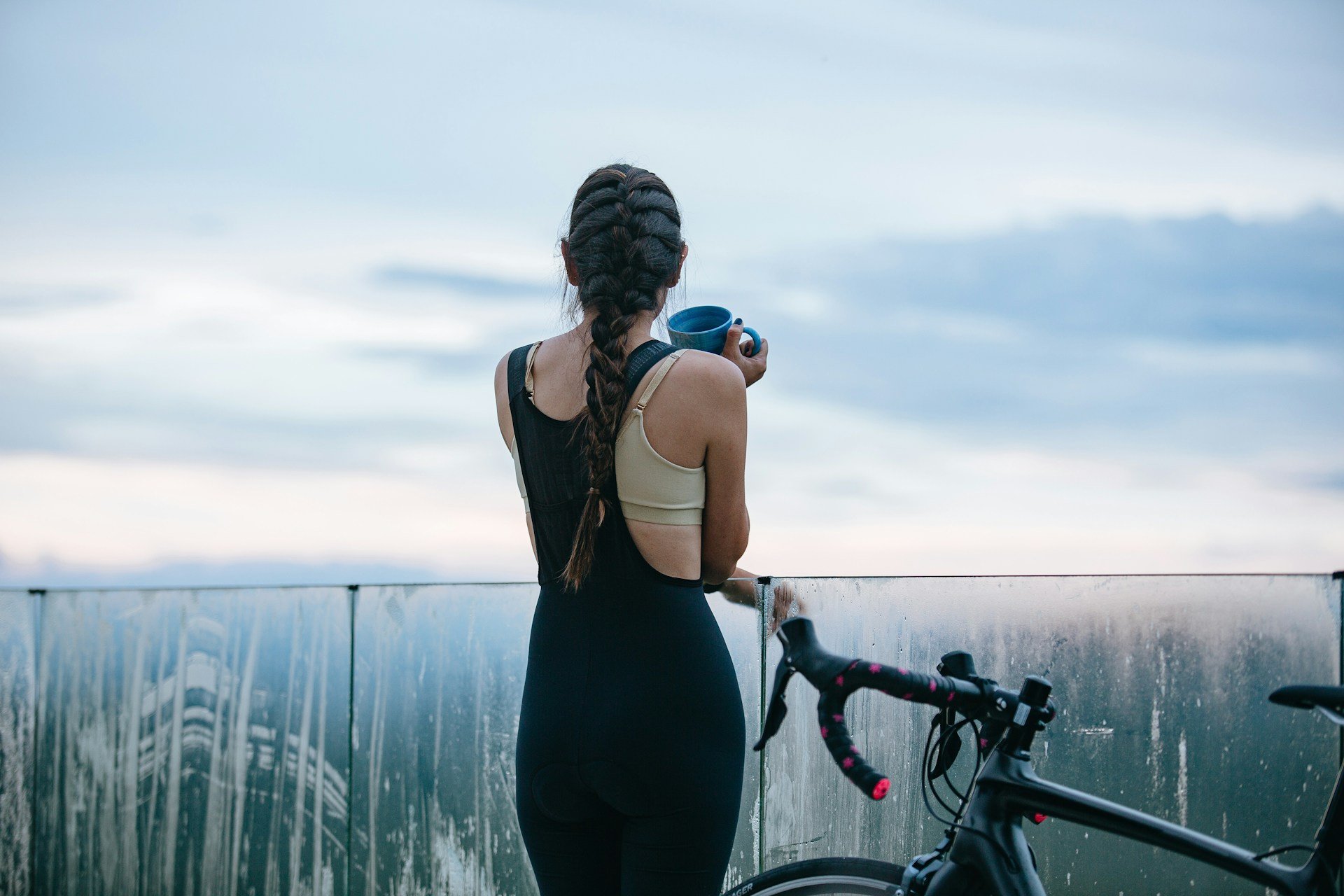 Cyclist holding coffee after a ride, highlighting recovery, endurance training and balanced wellness habits.