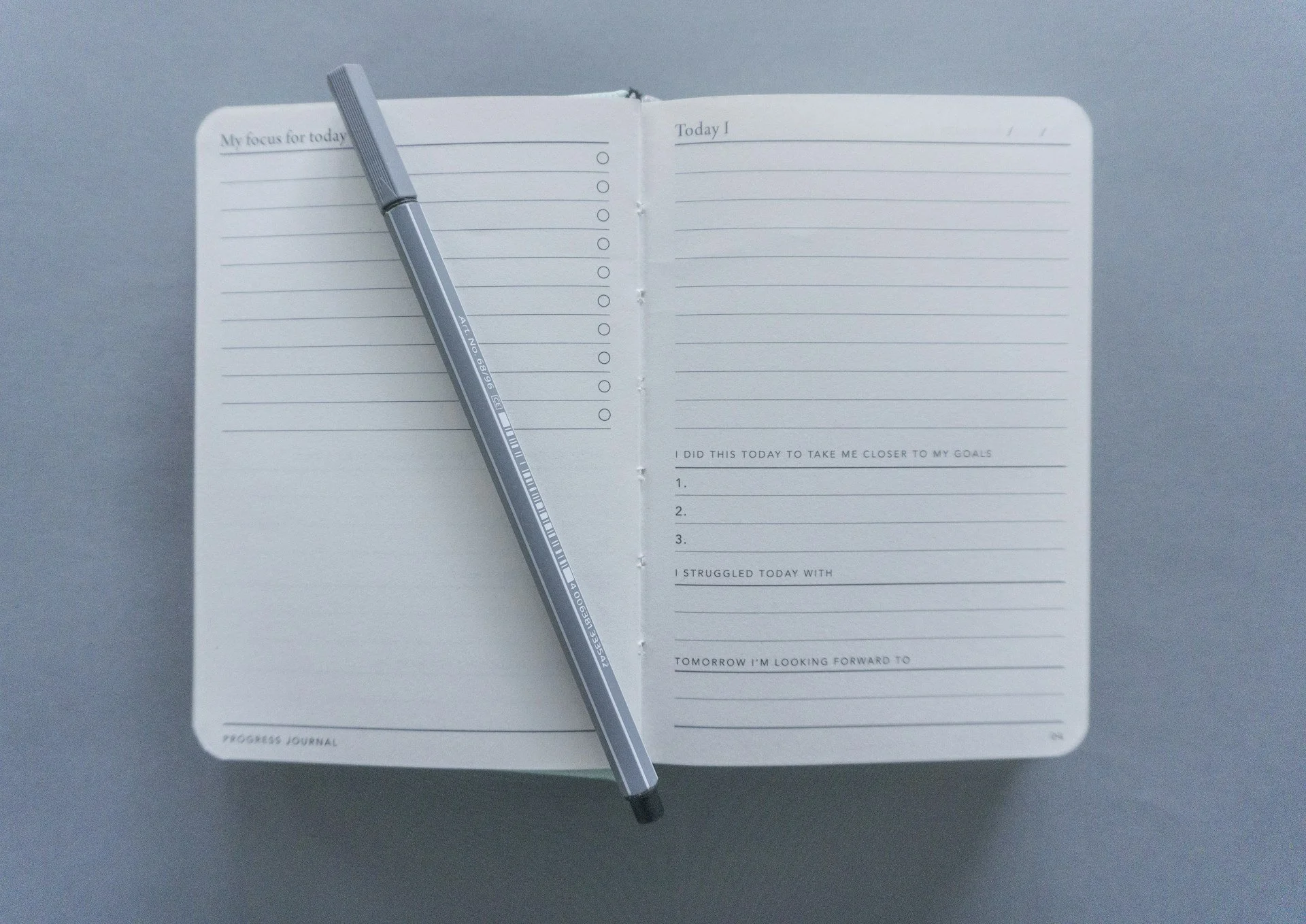 Open progress journal with a pen for tracking fitness goals and daily routines.