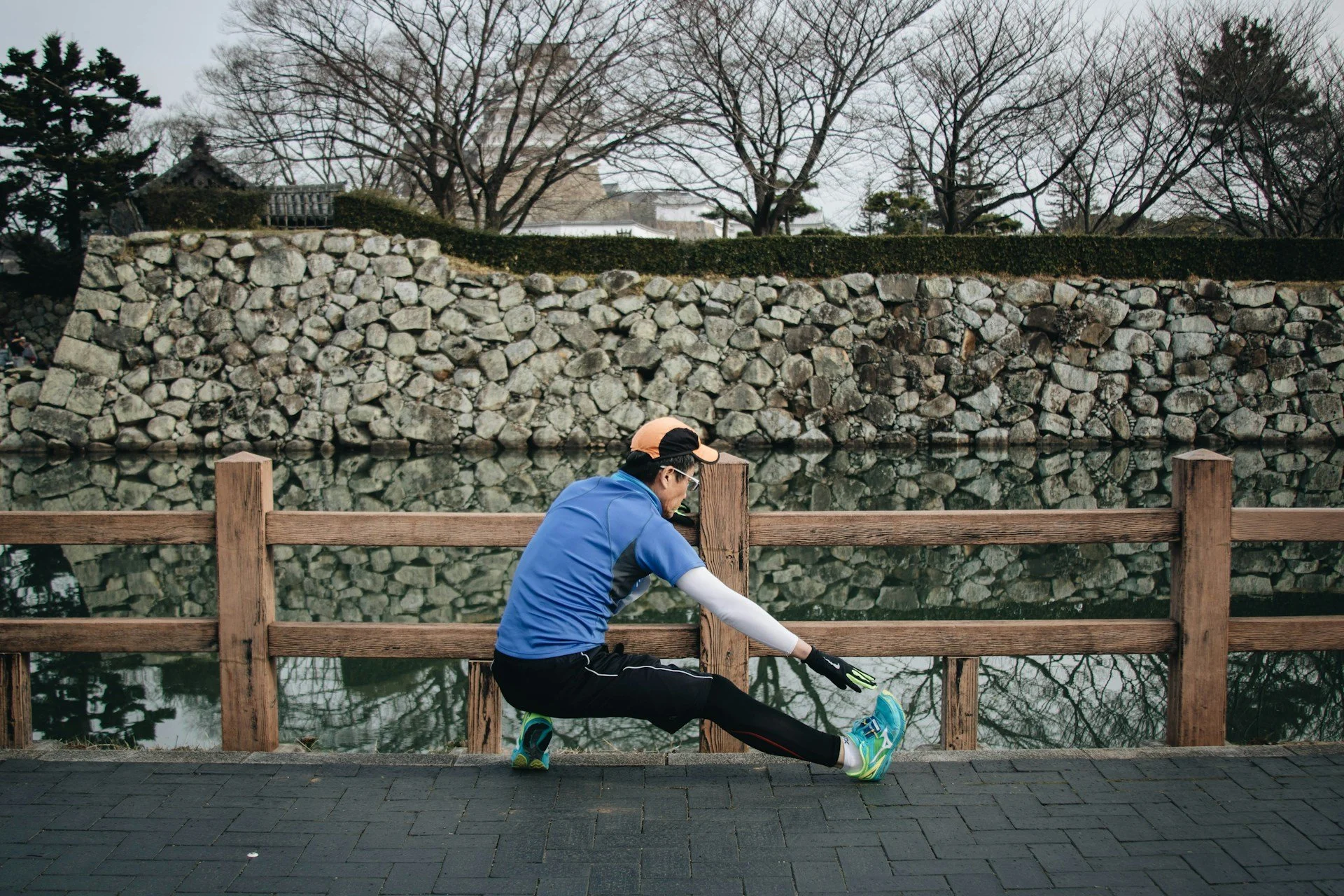 Runner stretching beside a stone wall after an outdoor workout.
