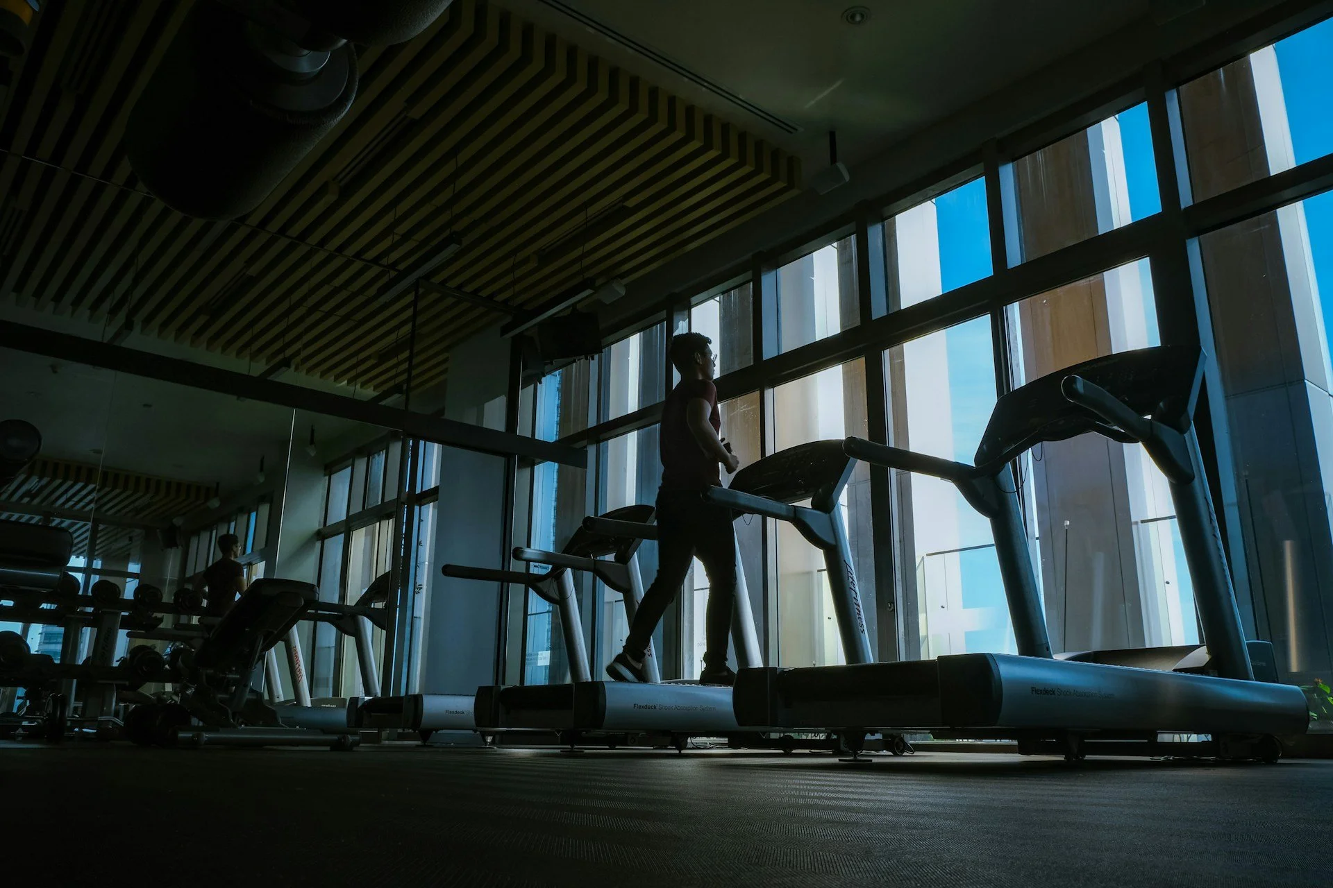 Person walking on a treadmill in a gym, highlighting low-impact cardio, walking workouts and heart health.