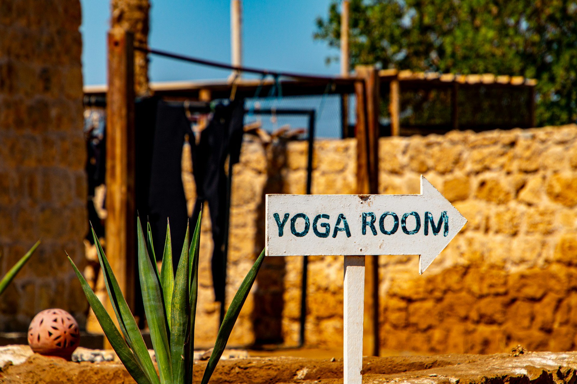 Outdoor yoga room sign pointing toward a wellness retreat space.