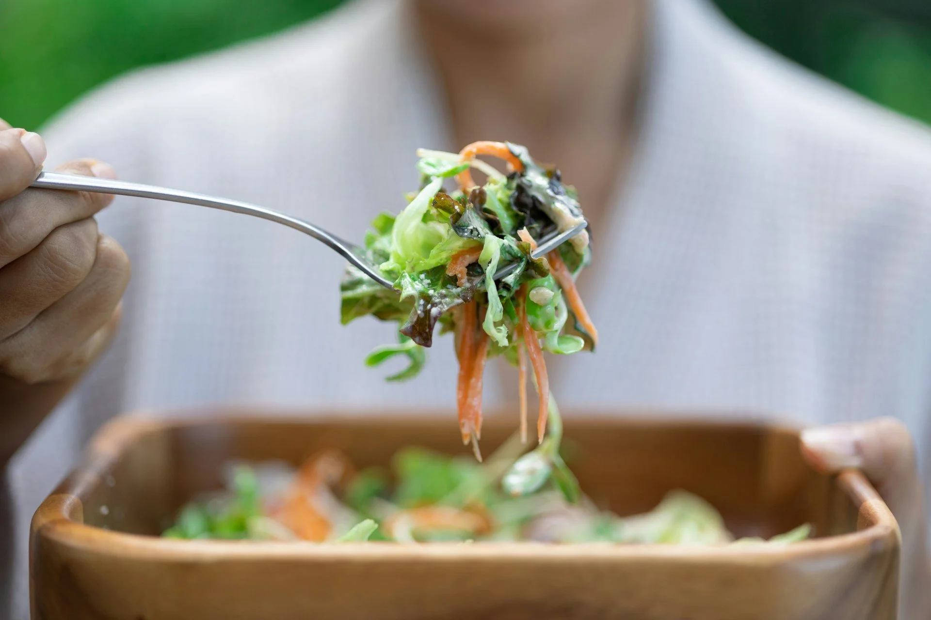 Person eating a fresh salad with leafy greens and vegetables, highlighting high fibre foods, gut health and everyday wellness.