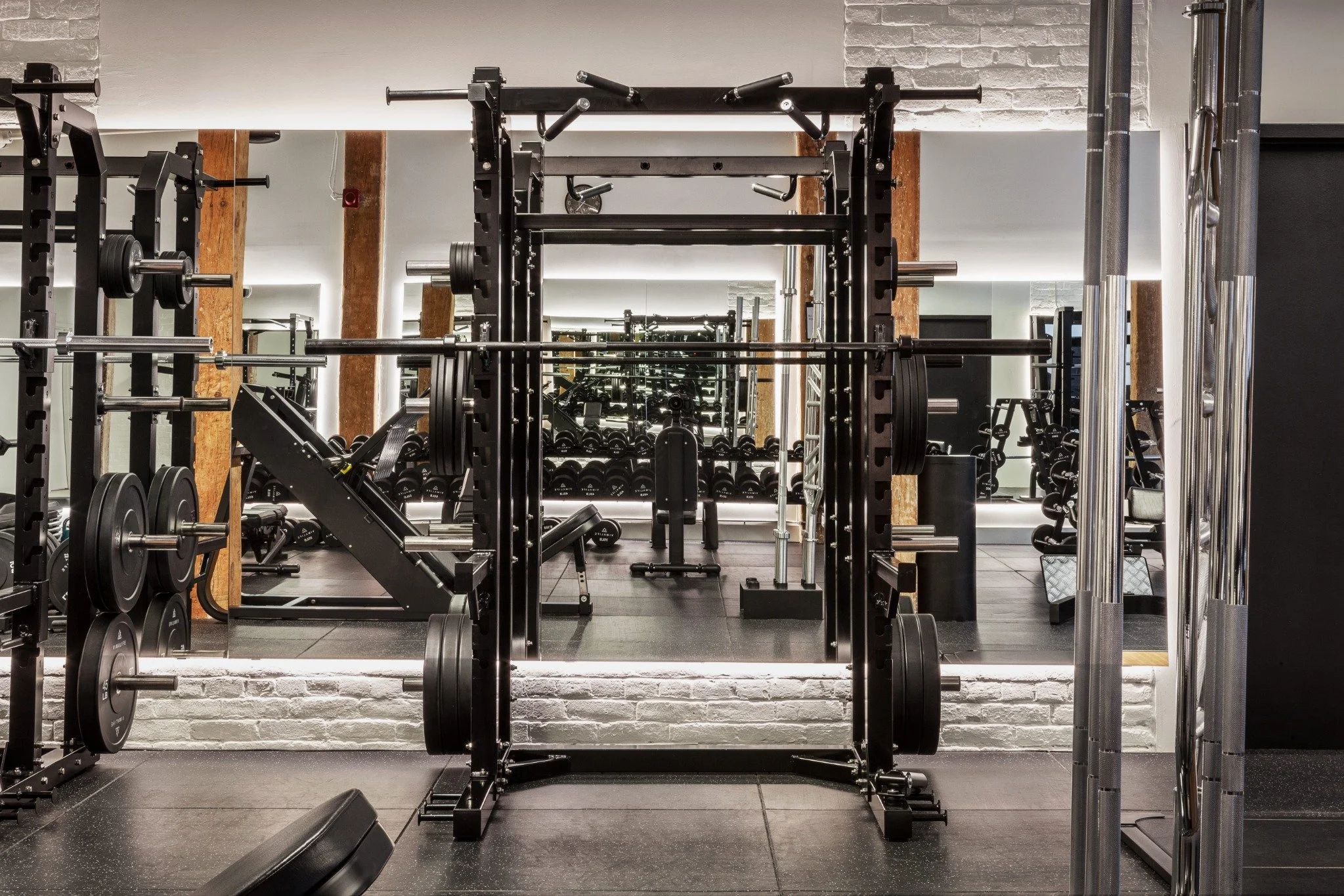 VIMALIFE strength training area with squat racks, barbells and free weights inside a boutique fitness club in Leslieville, Toronto.