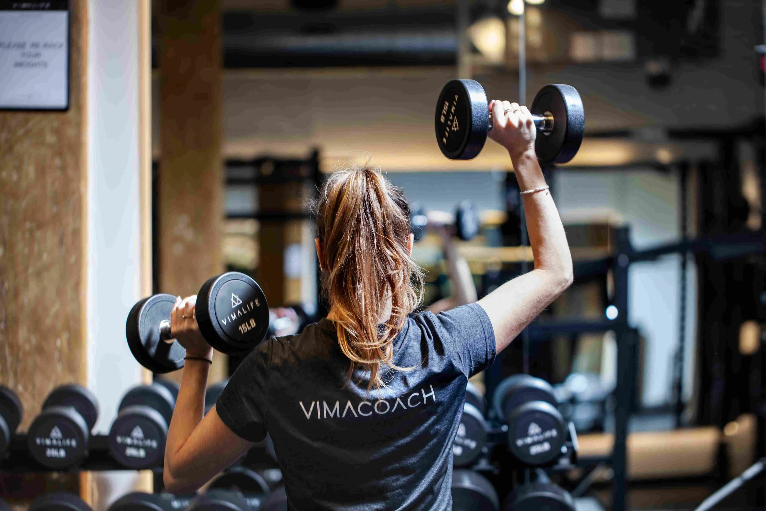 VIMACOACH lifting dumbbells on the VIMALIFE gym floor in Leslieville.