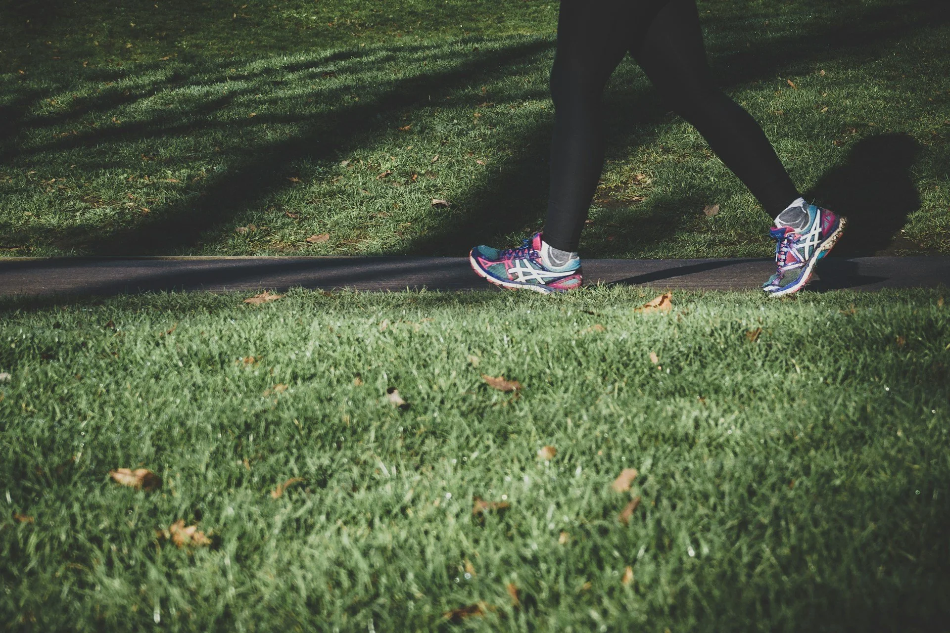 Person walking outdoors on a shaded path, highlighting low-impact cardio, daily steps and active recovery.