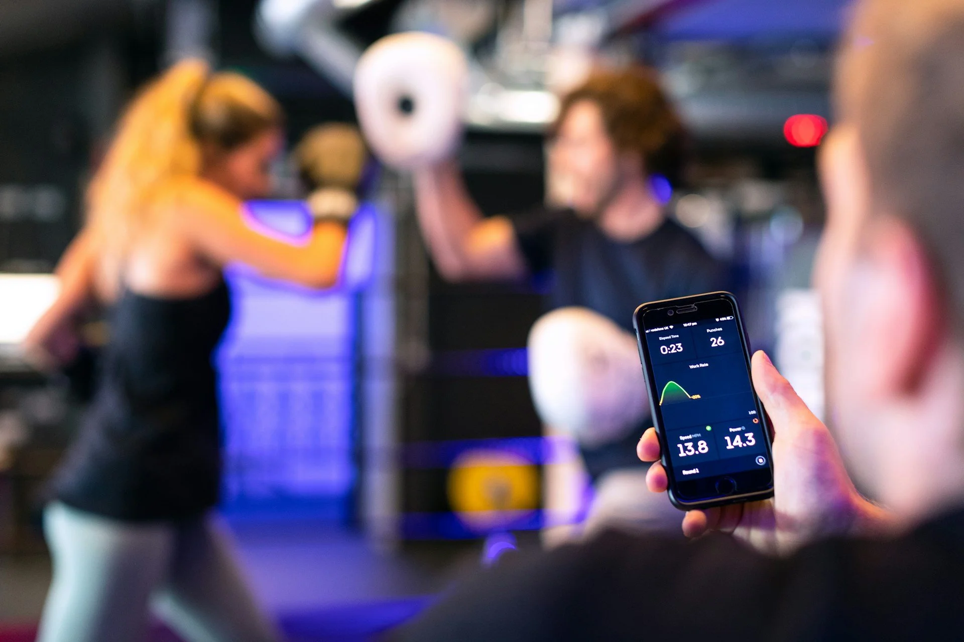 Person tracking boxing workout metrics on a phone during a high-intensity fitness session.
