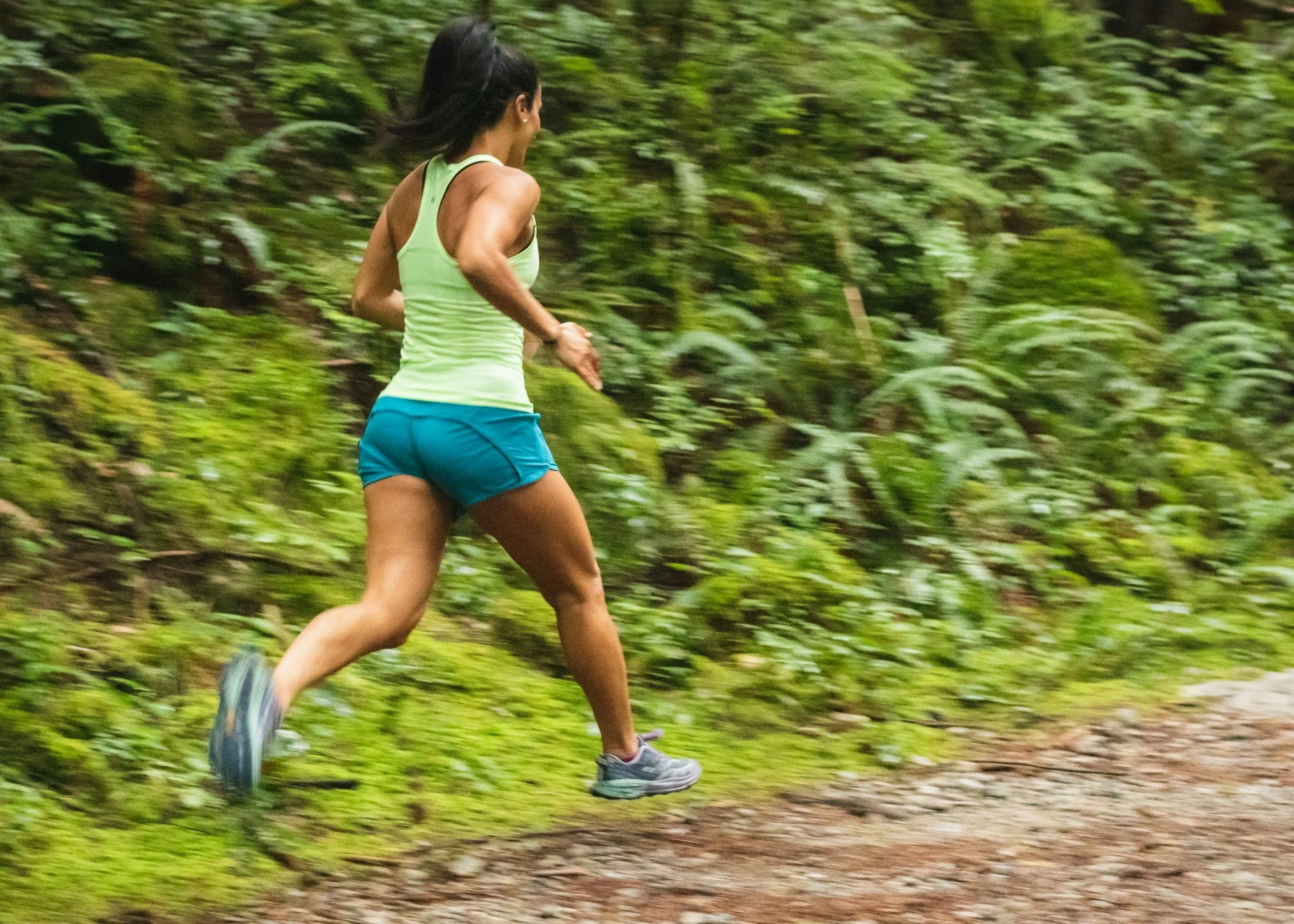 Woman running along a forest trail during an outdoor workout.