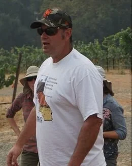 man in gray shirt and kakhi shorts standing in front of a large rock