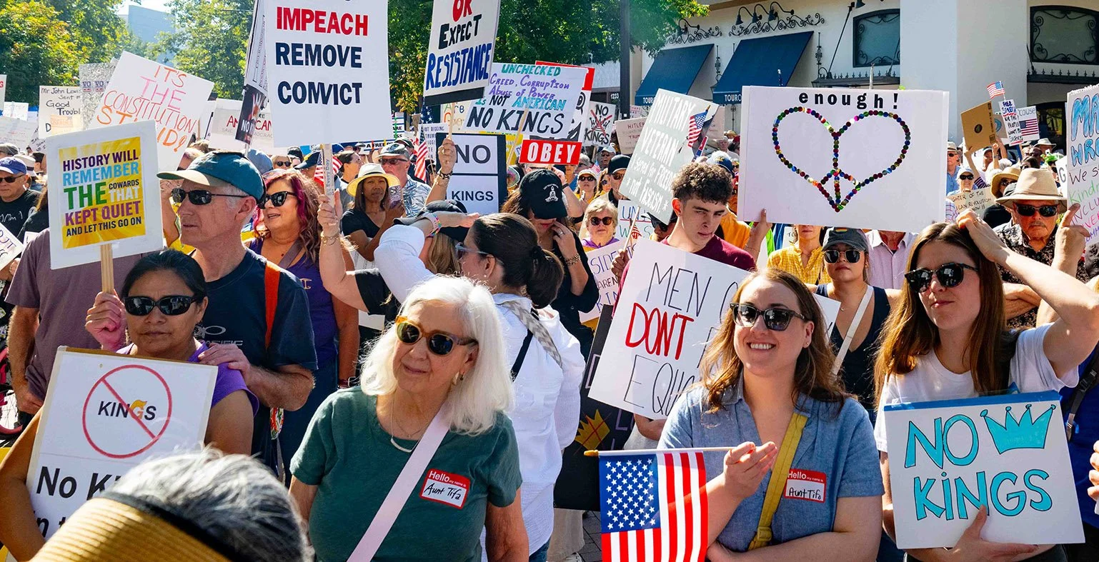 Demonstrators outside with No Kings signs