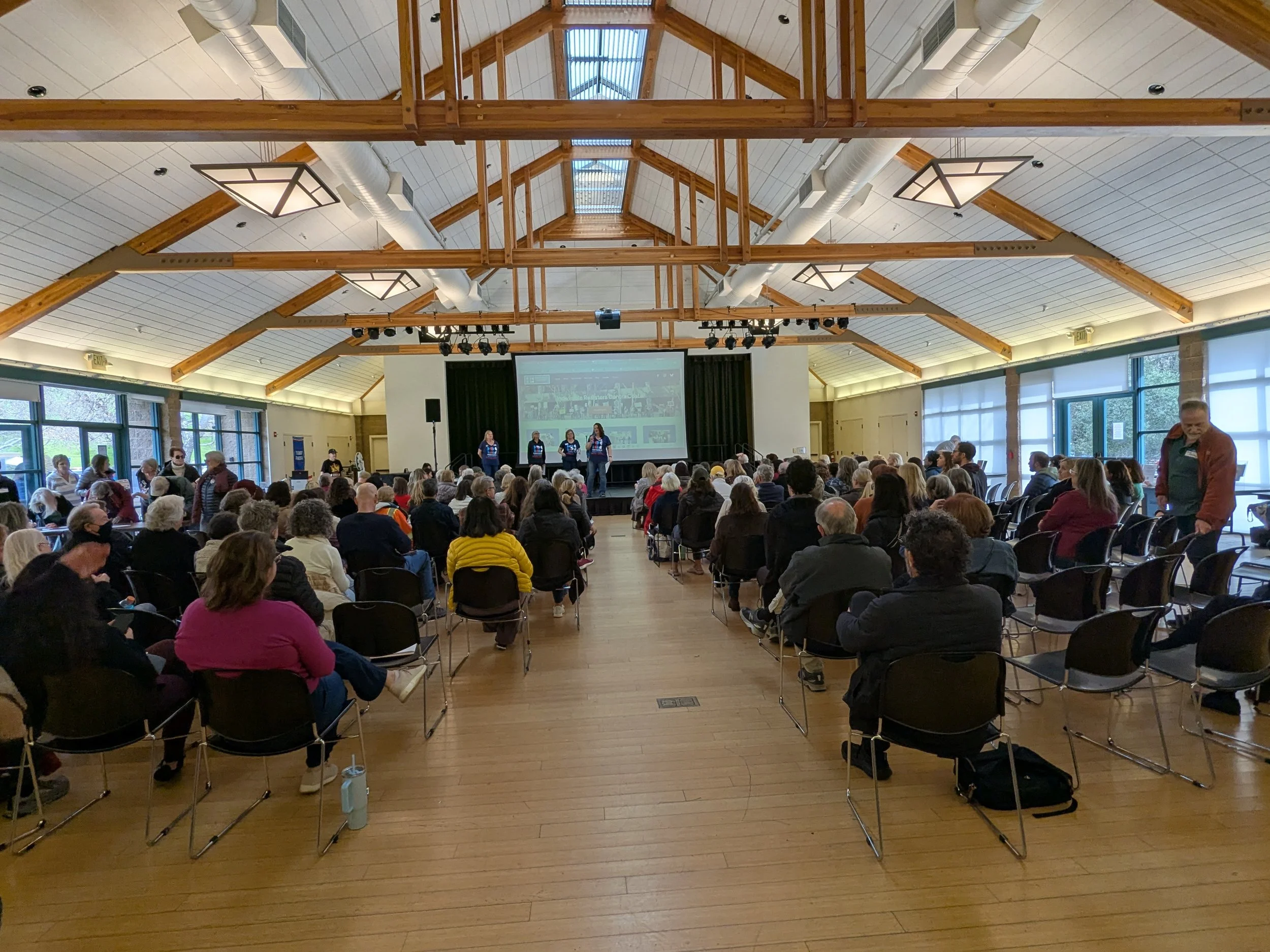 A large group of people shown seated in a community space