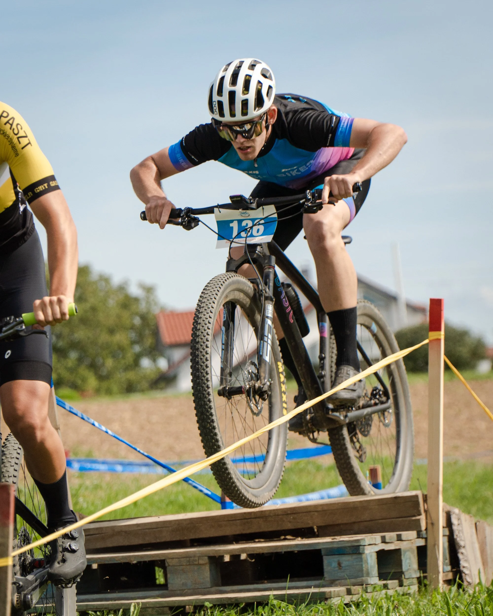 Ein Mountainbike-Fahrer im Radsportwettbewerb, der eine Holzrampe während eines Cross-Country-Rennens überquert.