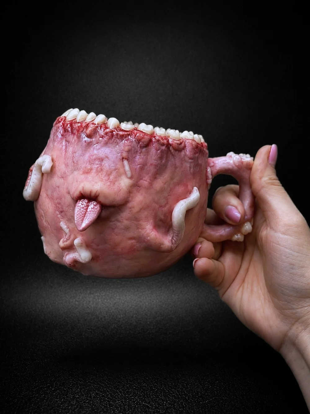 A flesh-pink mug with teeth around the rim, sticking its tongue out
