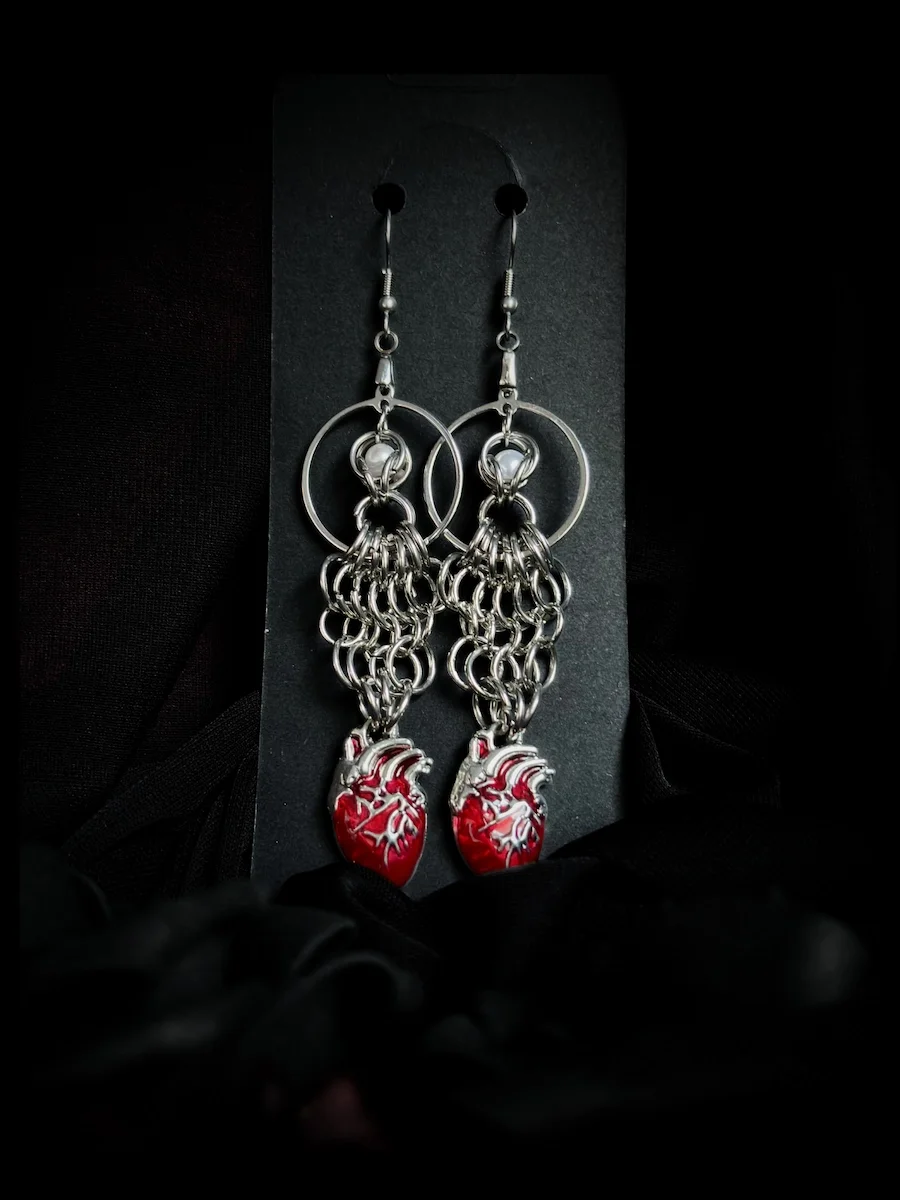 Heavy Heart chainmail earrings with red anatomical hearts and pearl bead held in hand