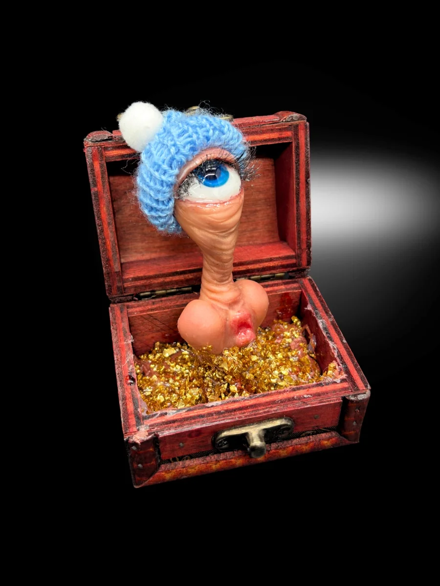 handmade conceptual art piece with single eye creature rising from gold box