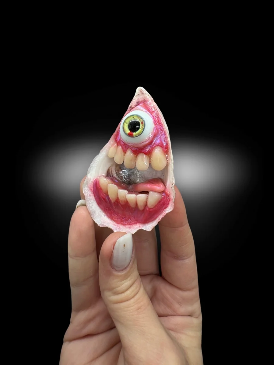 surreal oyster shell sculpture with teeth and glass eye monster inside