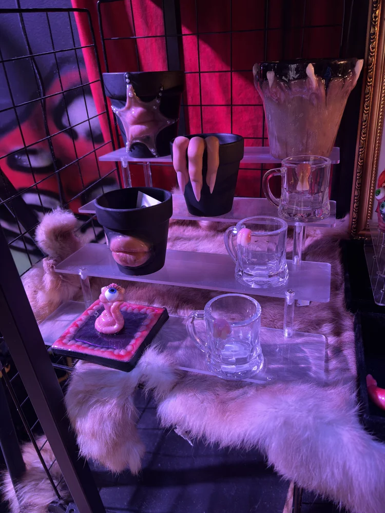 A toothy mug, a lip mug and a pink one-eyed piece on faux fur at Connect