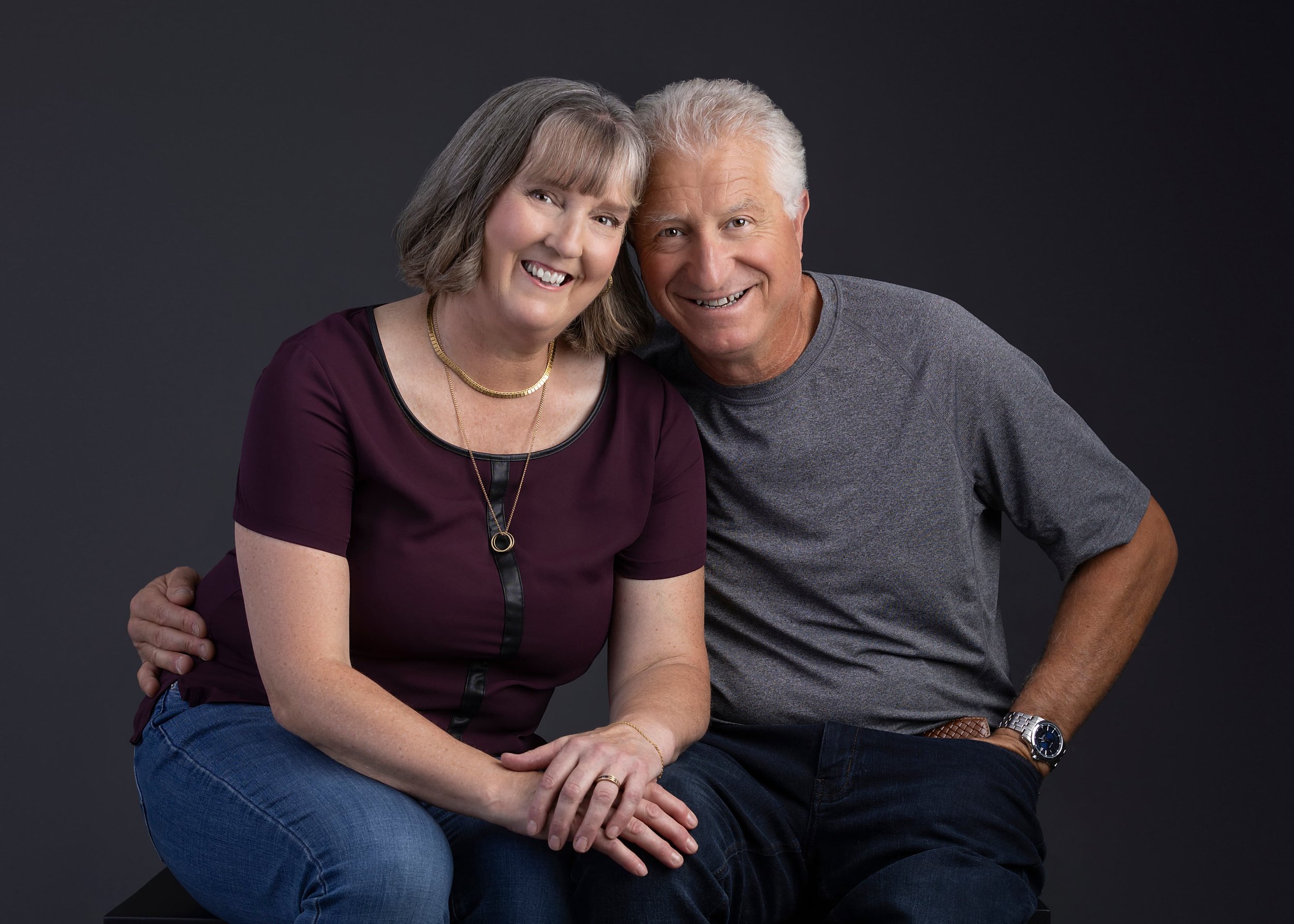 Cowichan valley best photographers Family Portrait couple portrait casual photoshoot Smiling elderly couple sitting close together against a dark gray background.