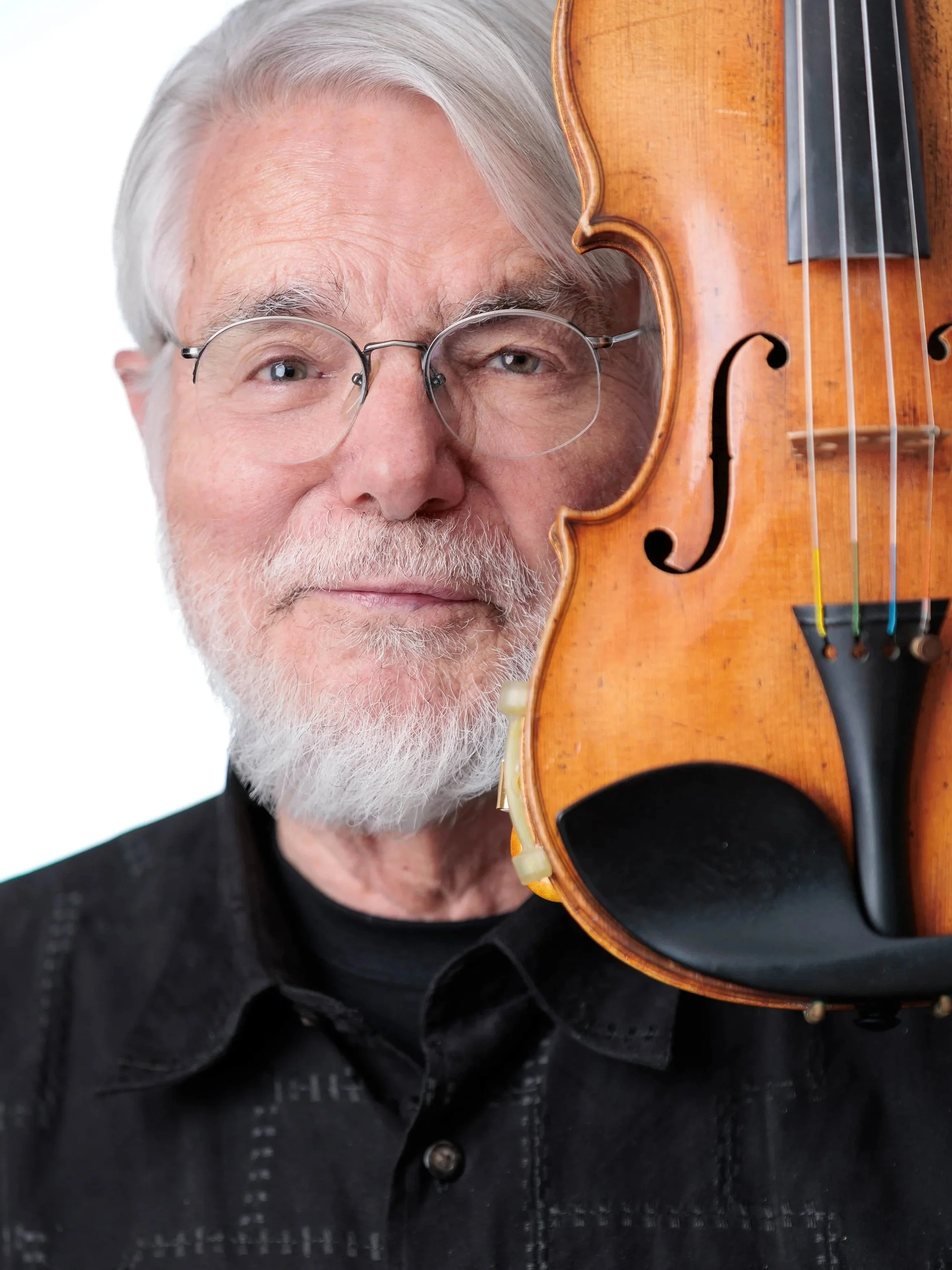 Glenn Mathieson Best Photographer Cowichan Duncan Mill BayAn elderly man with white hair, glasses, and a beard holding a violin close to his face.
