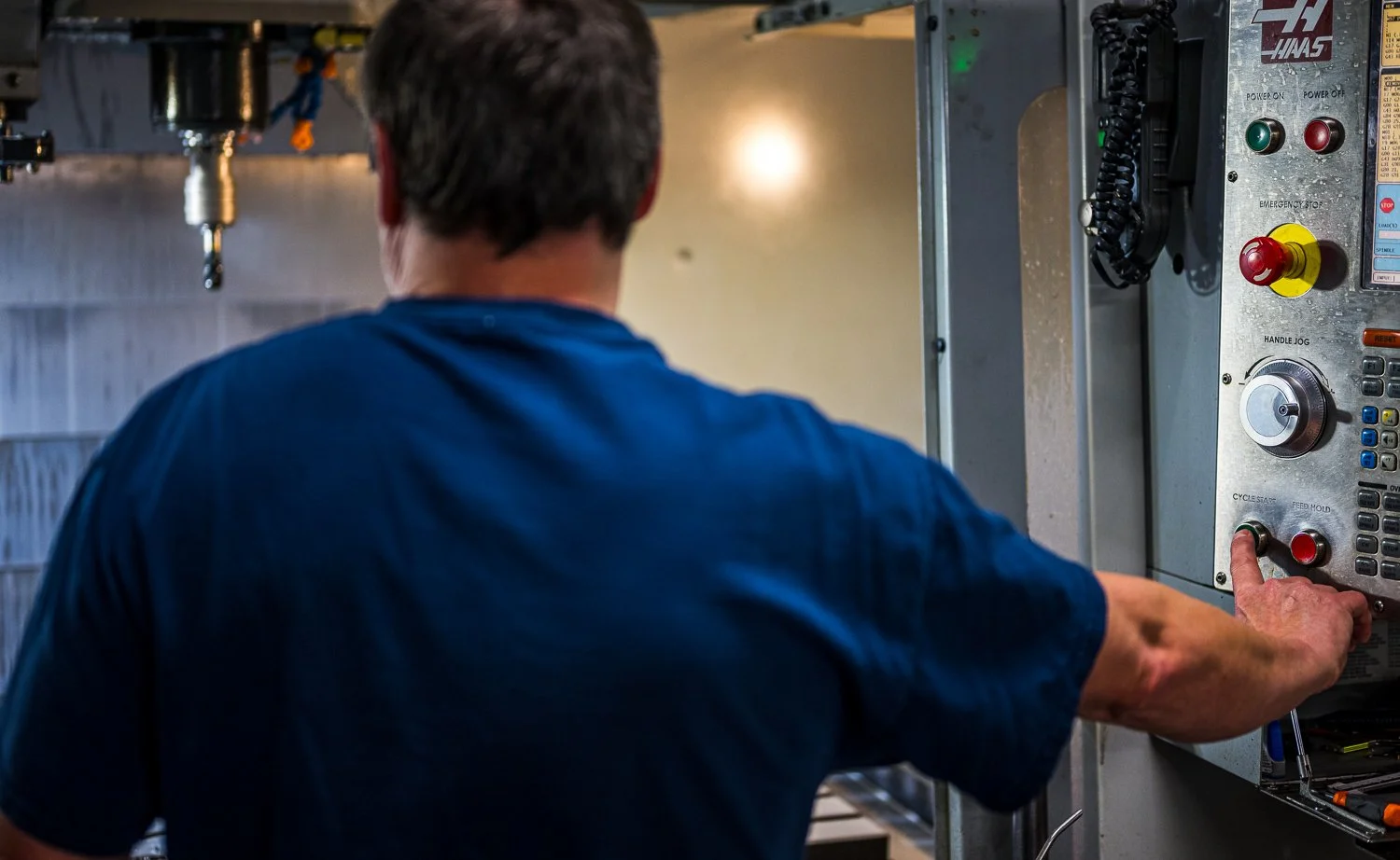 A person wearing a blue shirt operating industrial machinery in a factory setting.