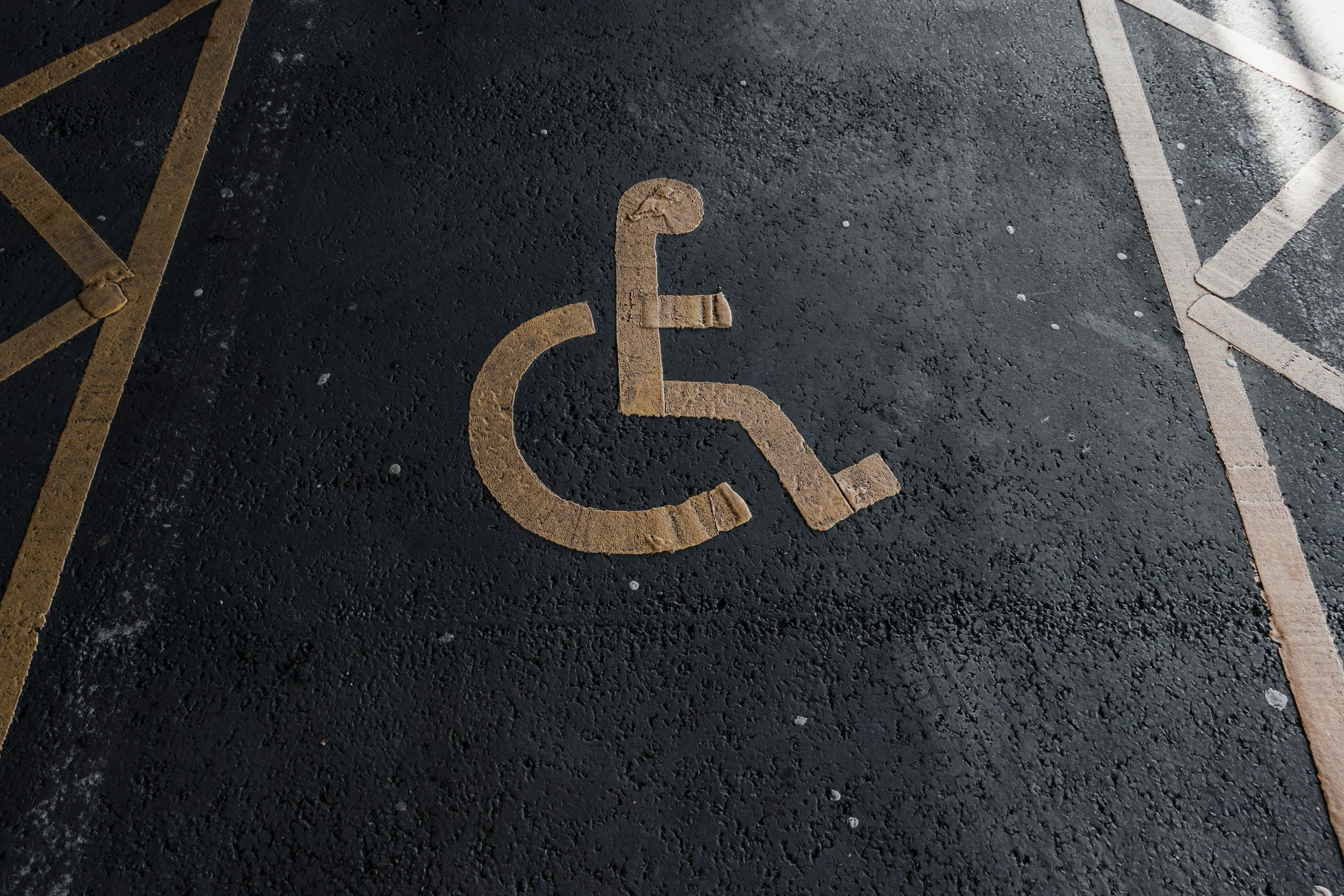 Handicap parking space painted on asphalt with a yellow wheelchair symbol.