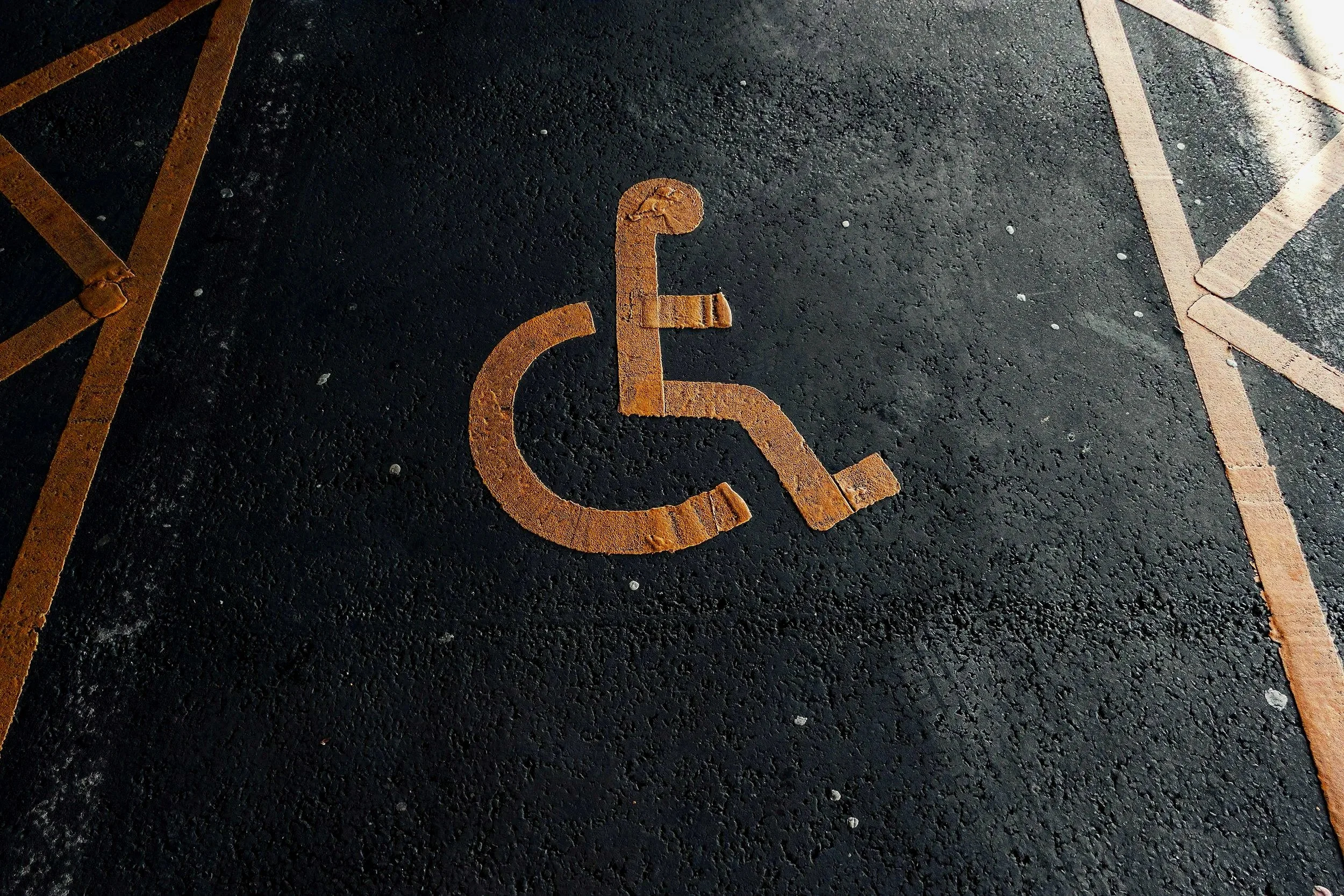 Handicapped parking space symbol painted in orange on the asphalt ground.