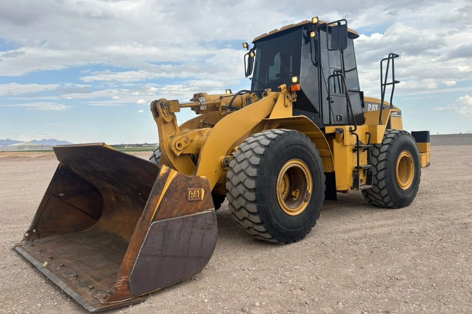 Retroexcavadora amarilla en un terreno despejado con cielo nublado.