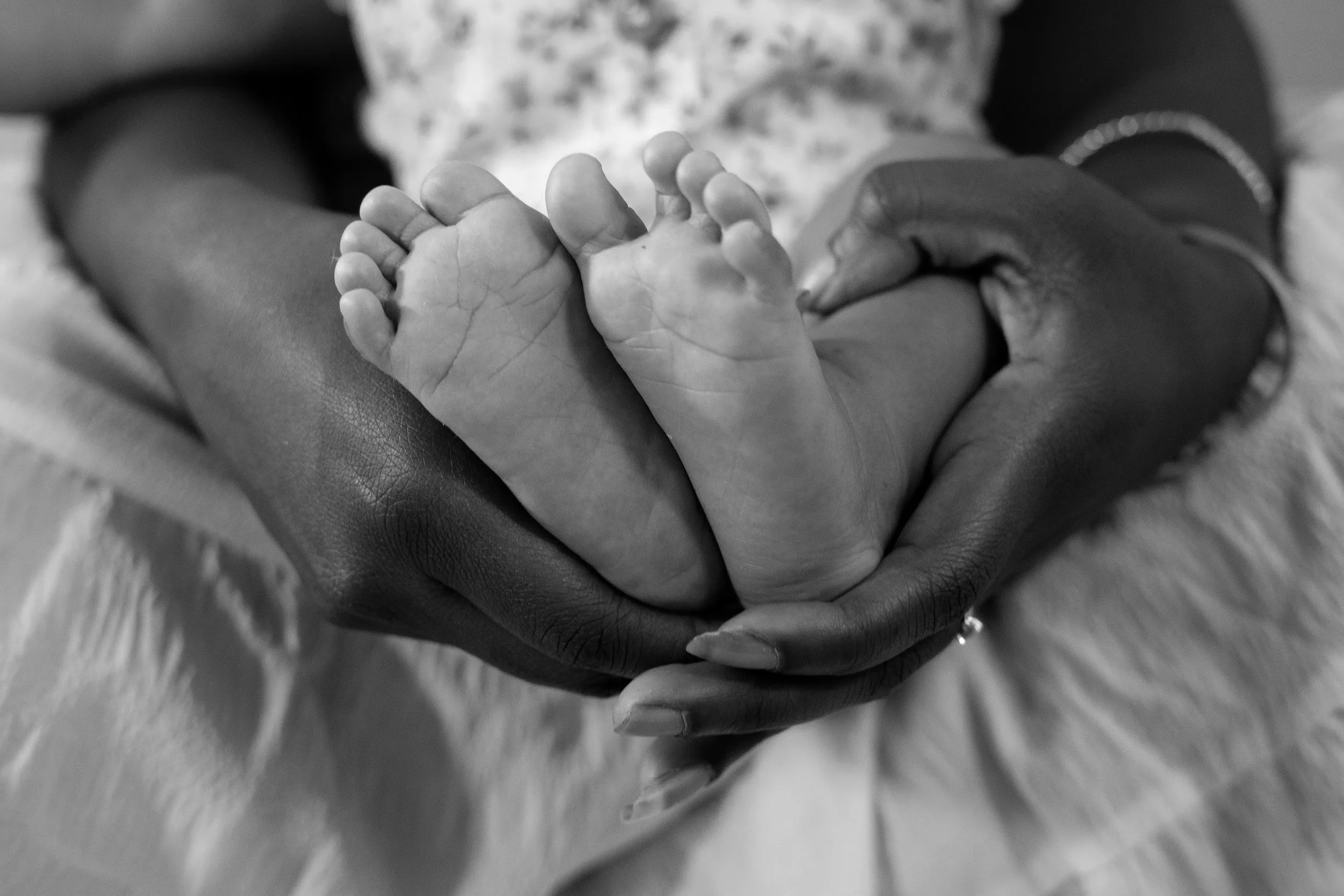 Black and white photo of an adult's hand gently holding a baby's feet.