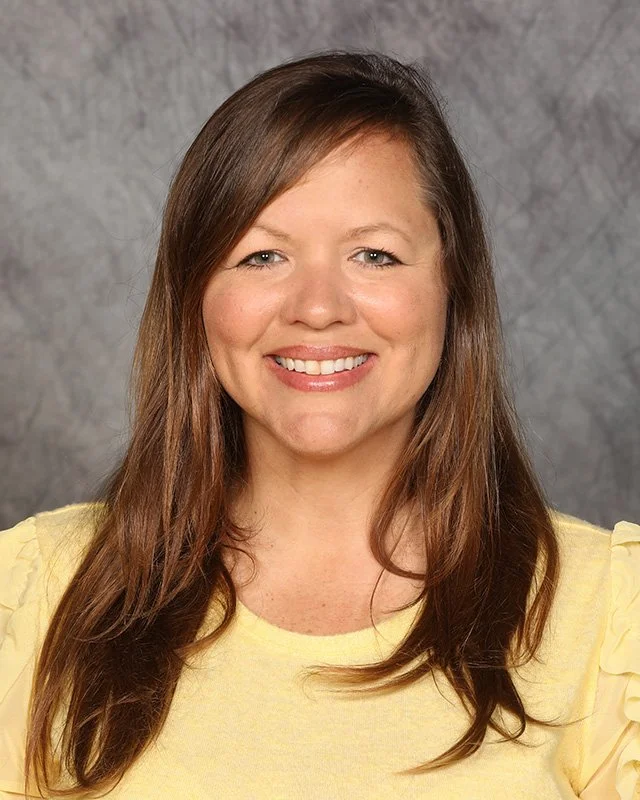 A woman with wavy dark hair, smiling big.