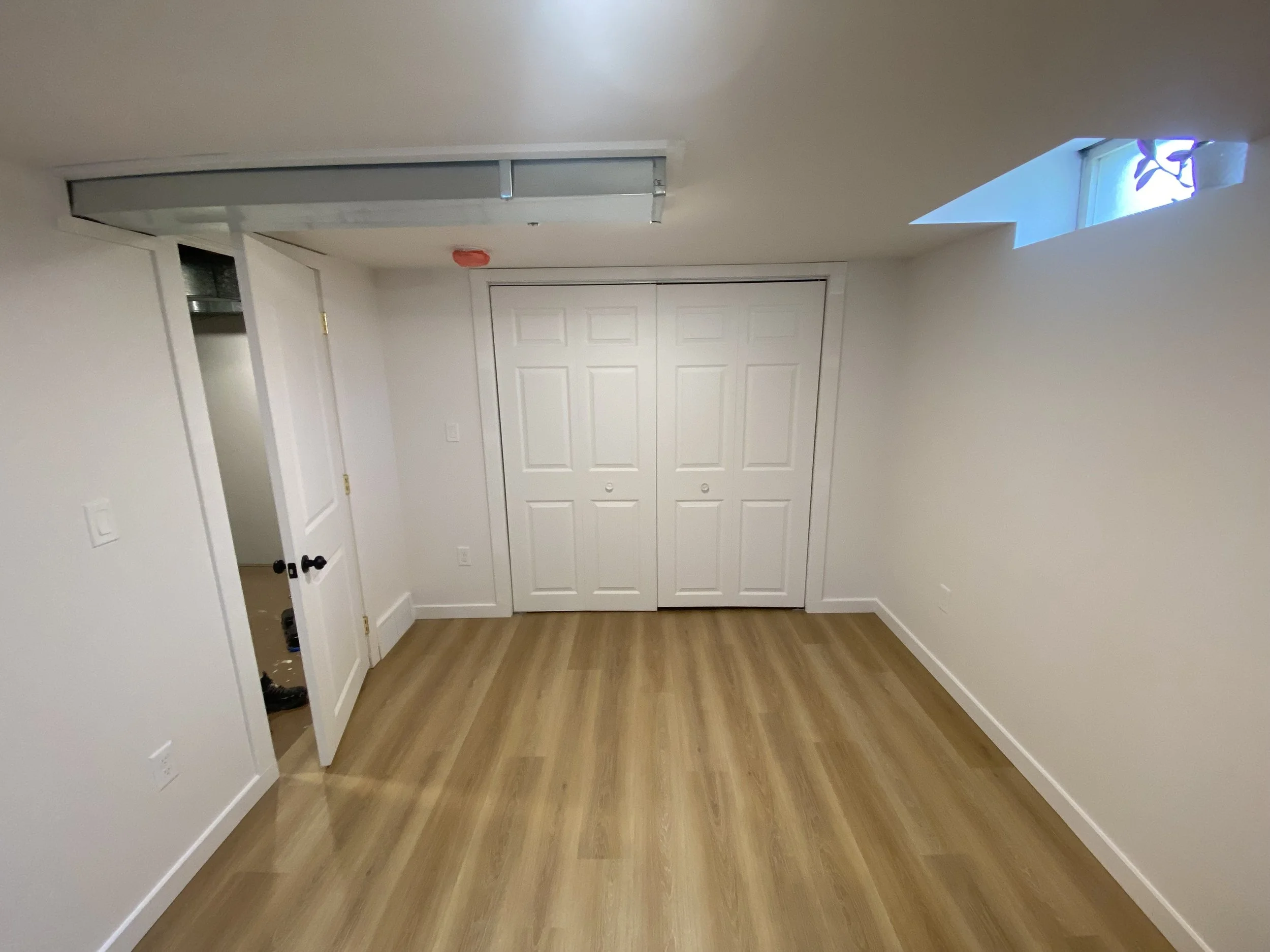 Basement bedroom with LVL flooring and sliding closet door