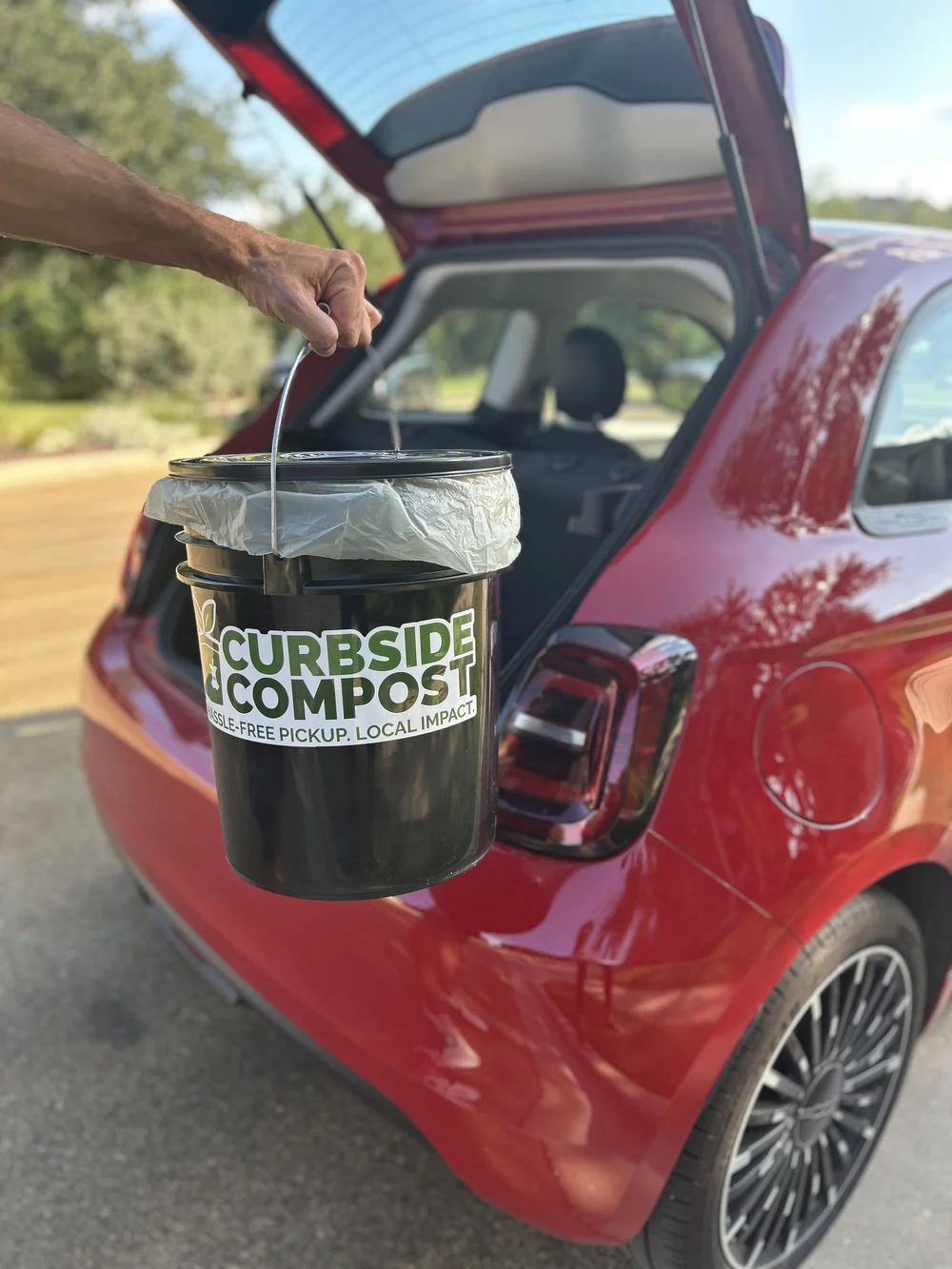 Curbside Compost bin being loaded into car for pickup