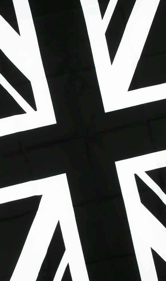 Close-up of a fabric with a black background and white geometric shapes resembling parts of the Union Jack flag.