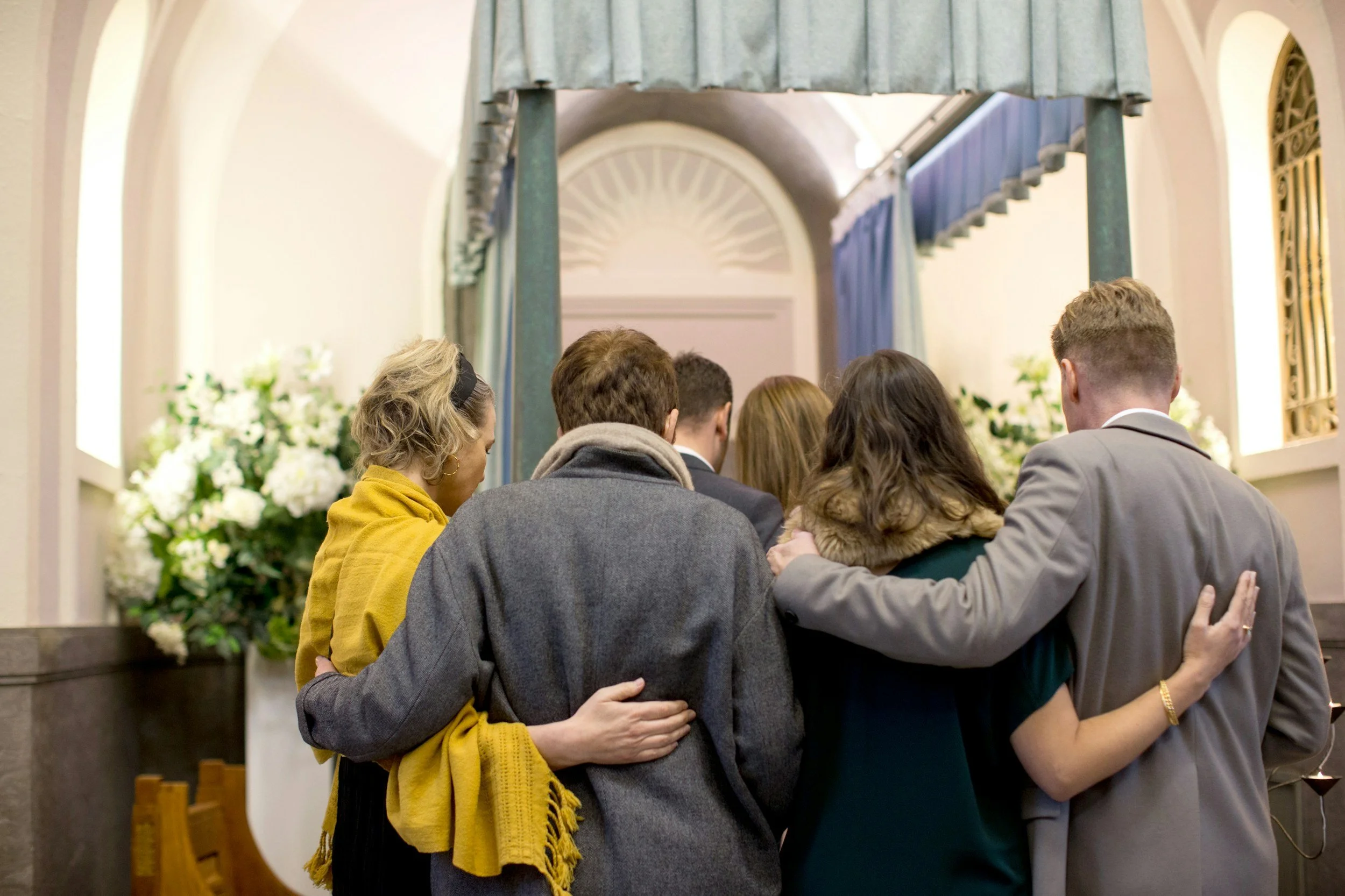 Group of people embracing and praying together at a church altar during a religious service.