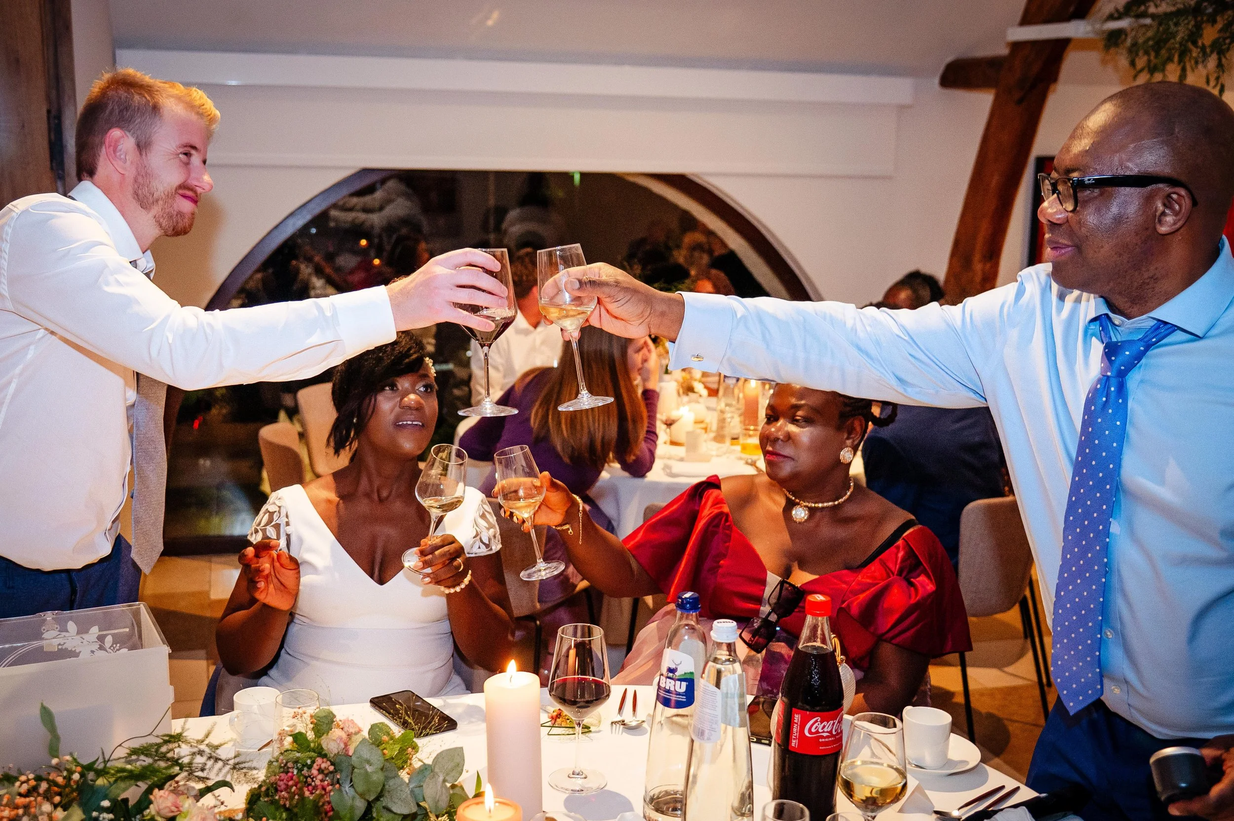 Mensen die proosten tijdens een feestmaal in een restaurant, met decoraties en wijn in een warme sfeer.