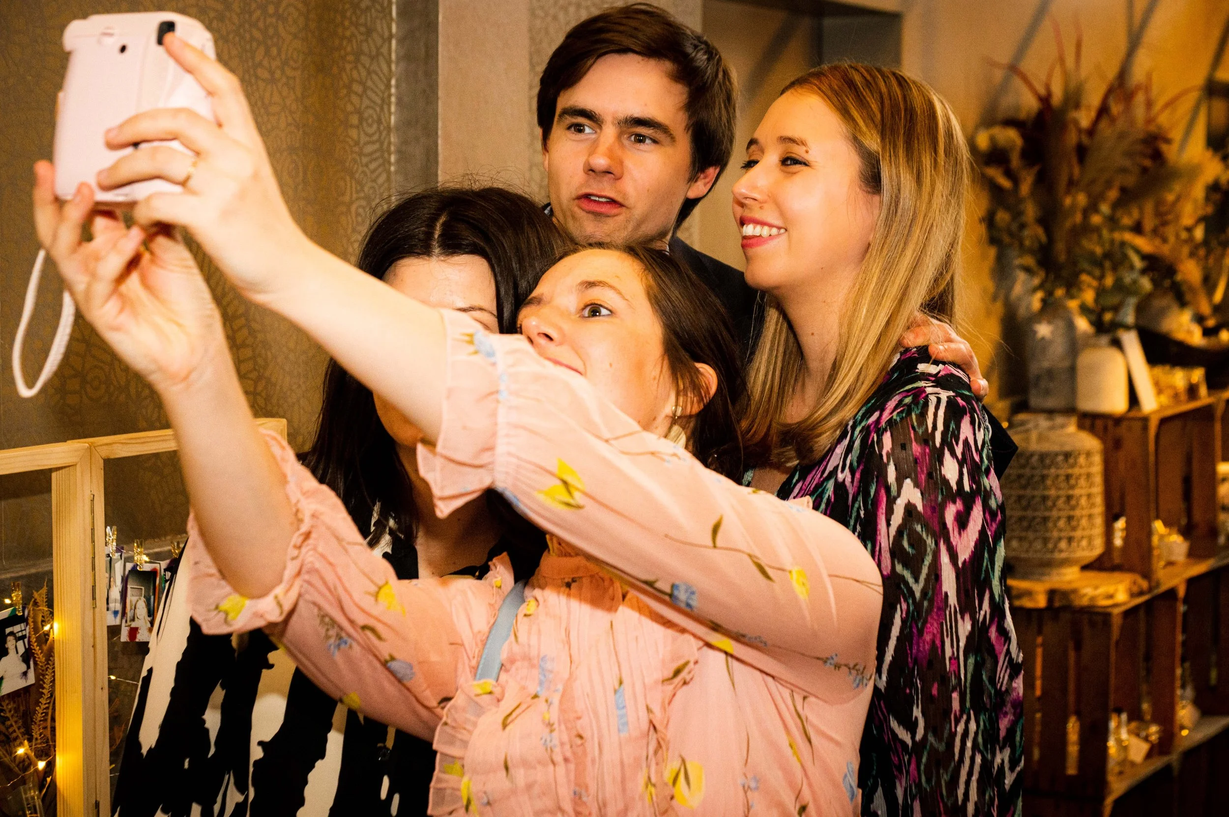 Vijf vrienden maken een groepsselfie in een gezellig interieur.