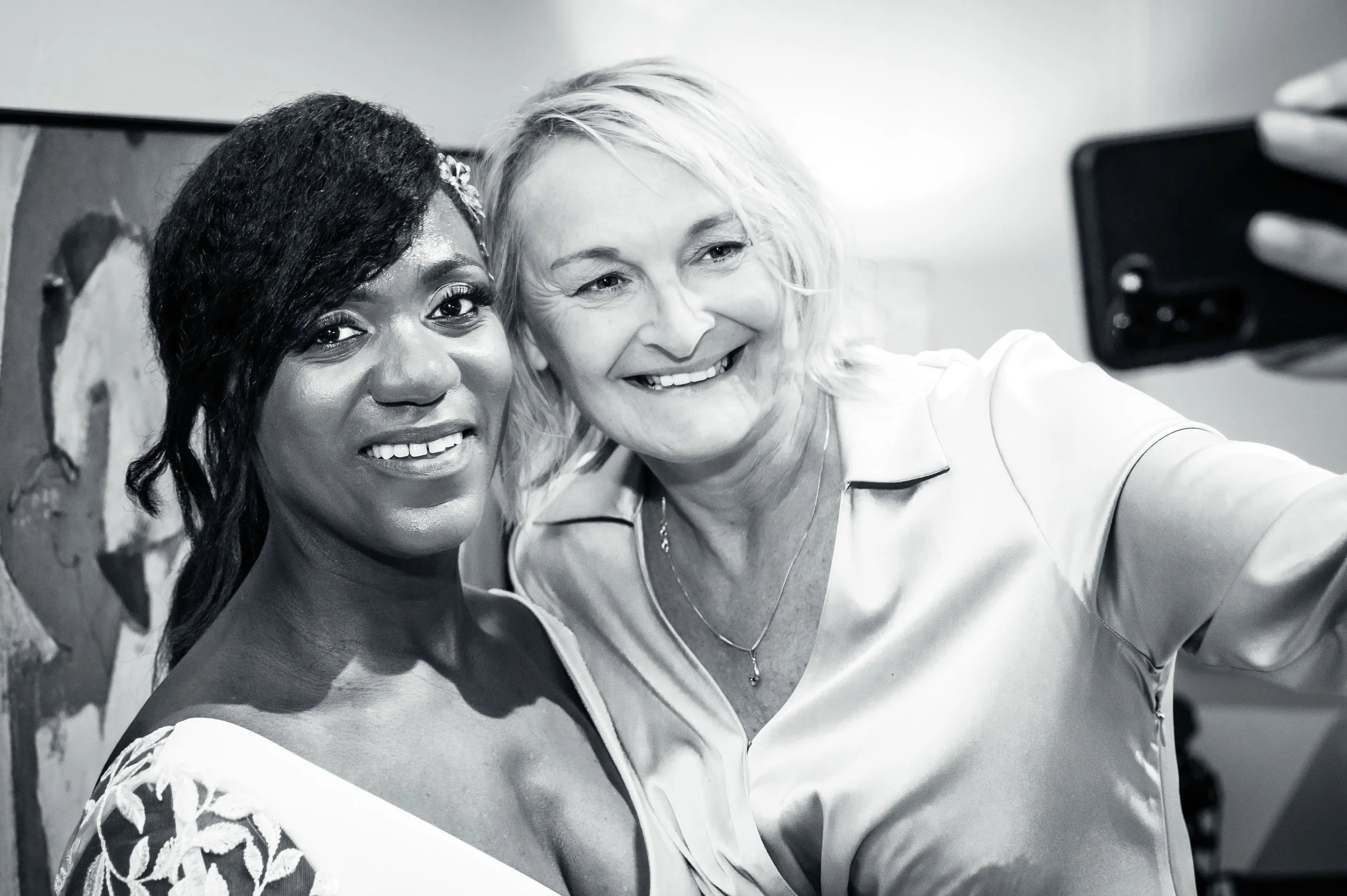 Twee vrouwen nemen een selfie, lachend en kijkend naar de camera, in een zwart-wit foto