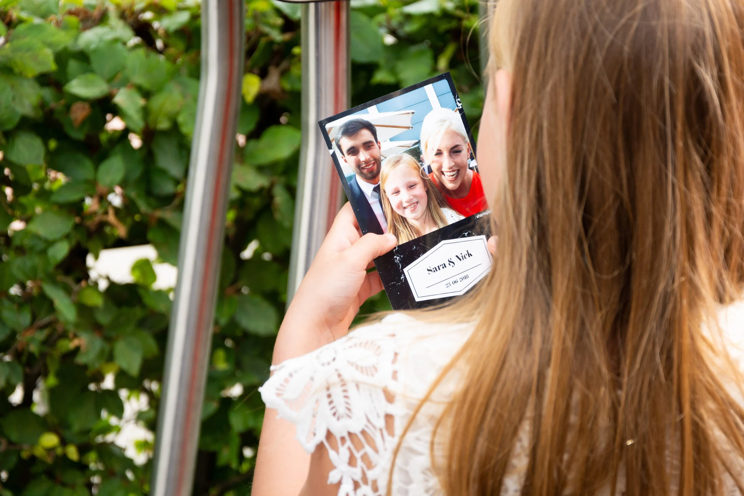 Een vrouw houdt een fotolijst vast met een foto van drie mensen, drie generaties, die lachen en poseren voor de camera.