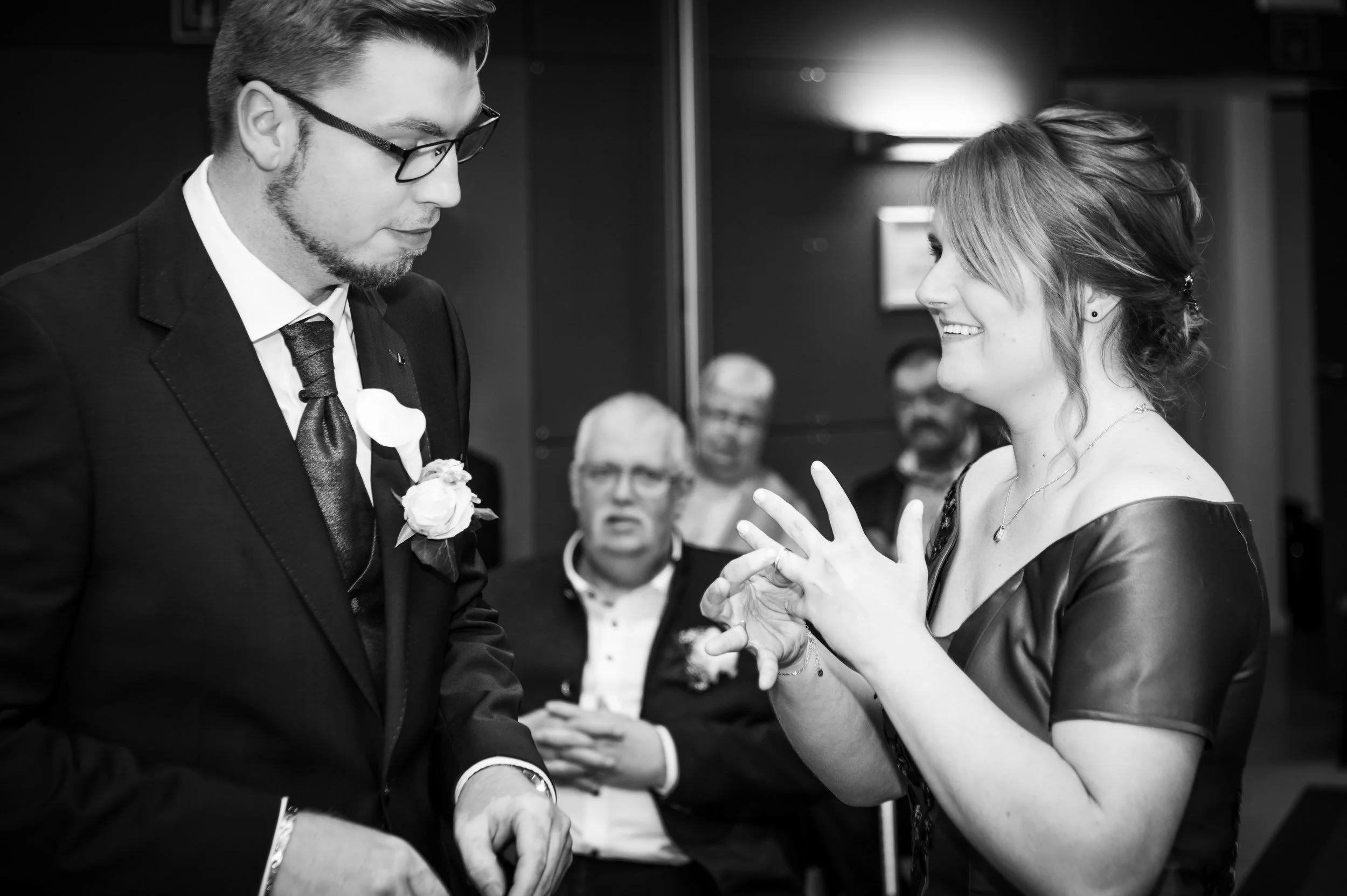 Een vrouw en een man die in een formele setting met elkaar praten, omringd door andere mensen.