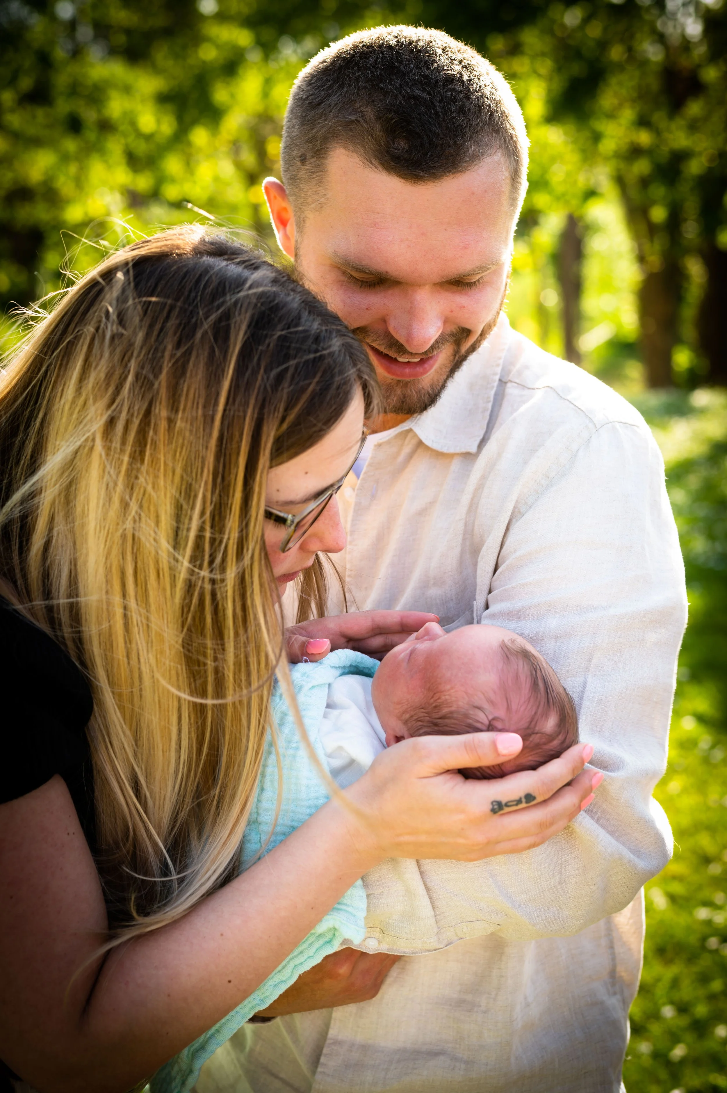 Een jong echtpaar houdt een pasgeboren baby in een bosachtige omgeving.