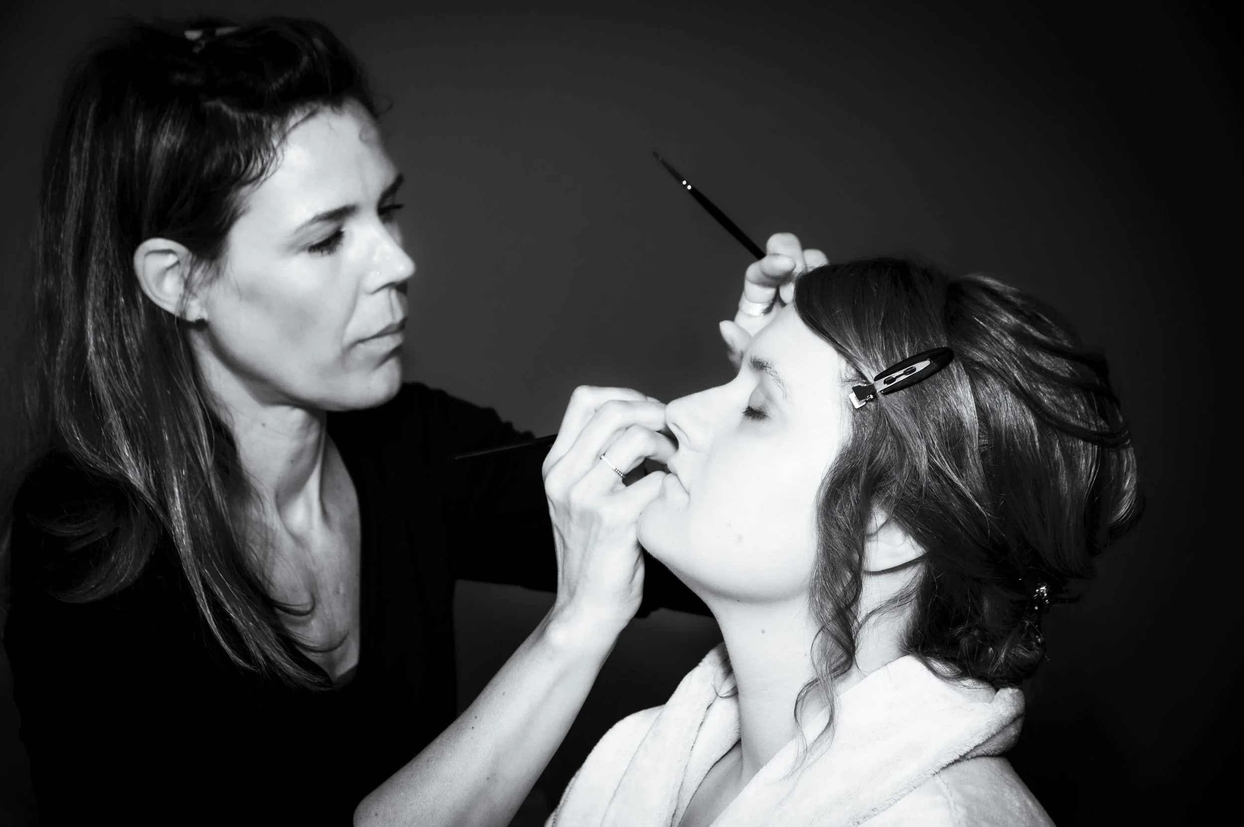 Make-up artiest die de oogmake-up van een vrouw aanbrengt in een studio