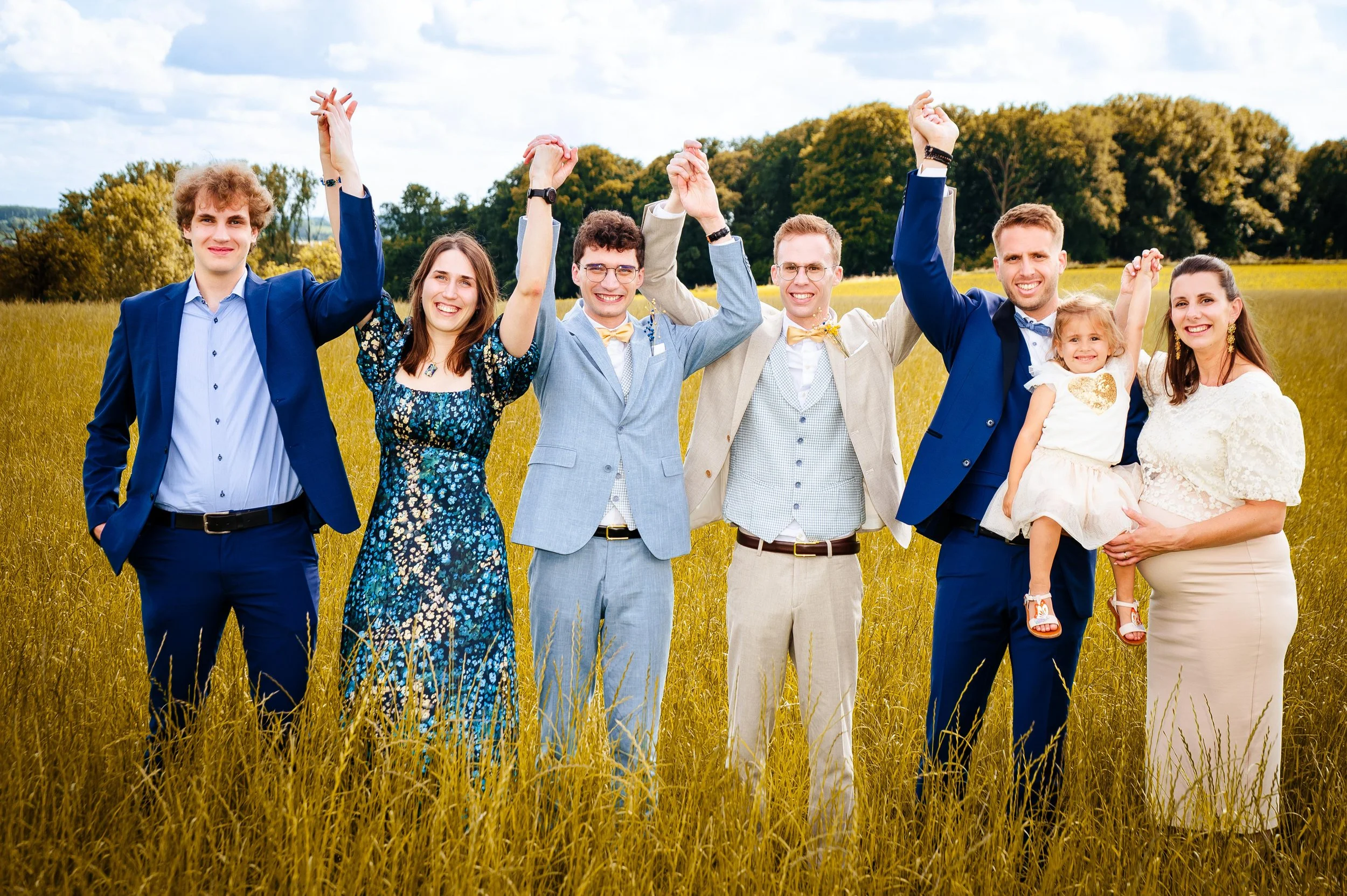 Gelukkige mensen die hand in hand staan in een veld met groen bos op de achtergrond, ze vieren een speciale gelegenheid.