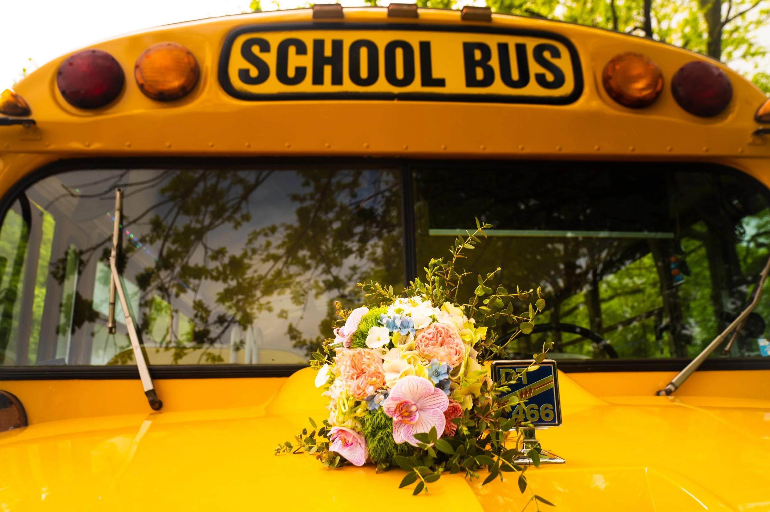 Gele schoolbus met bloemen op de motorkap.