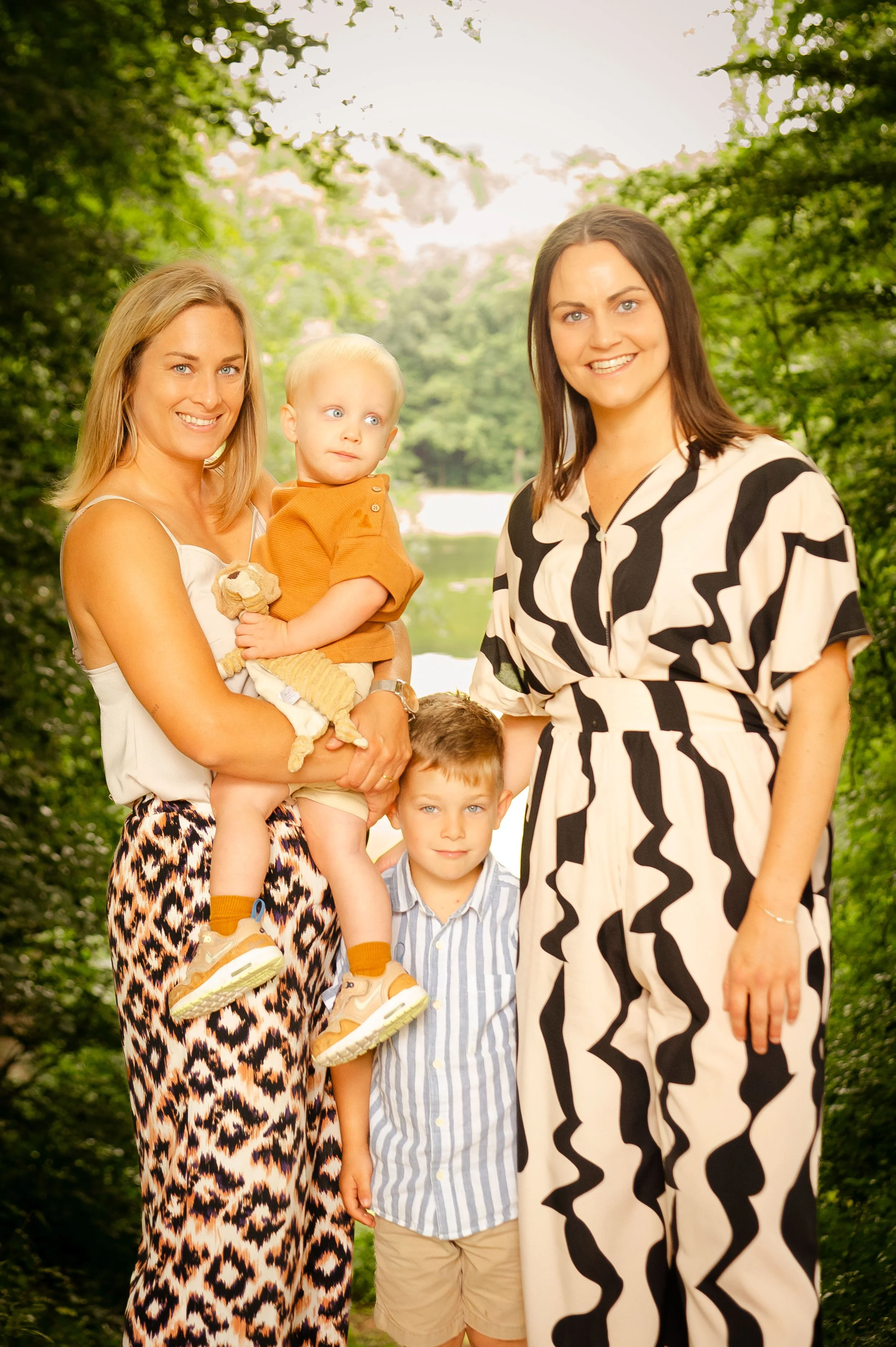 Twee vrouwen en twee kinderen in een bos, zomers, glimlachend.