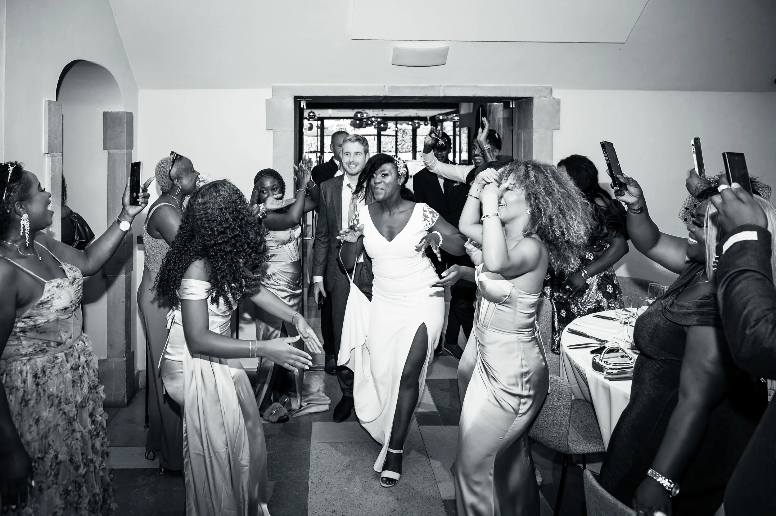 Mensen dansen en vieren op een feest of bruiloft, met een vrouw in een witte jurk die in het midden danst.