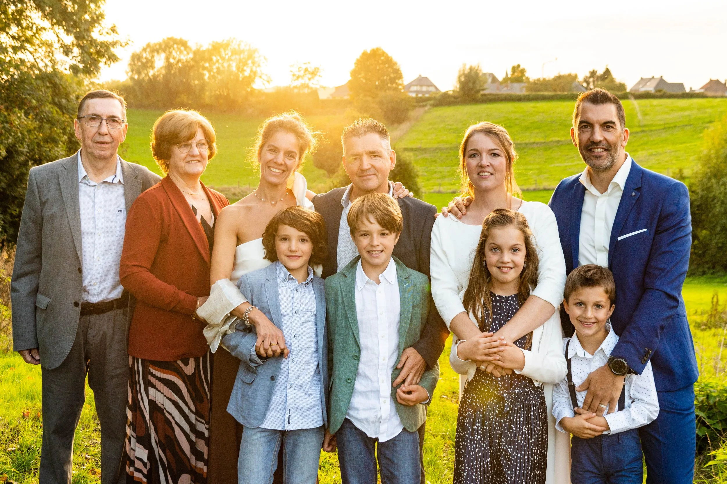 Gezelschap van tien mensen, inclusief kinderen en volwassenen, in een groen landschap bij zonsondergang.