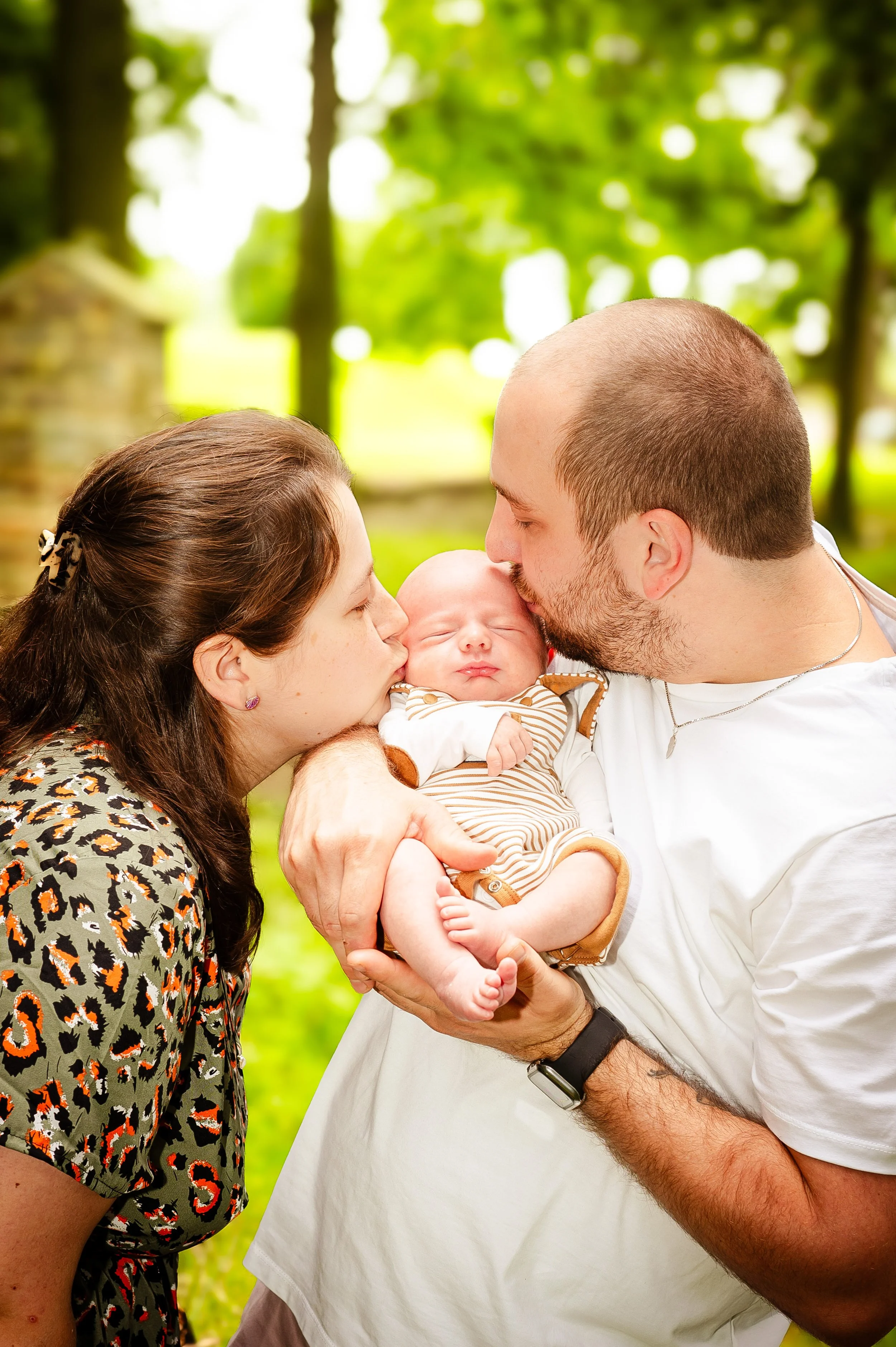 Een jong gezin met een baby in een bos, kusend de baby.