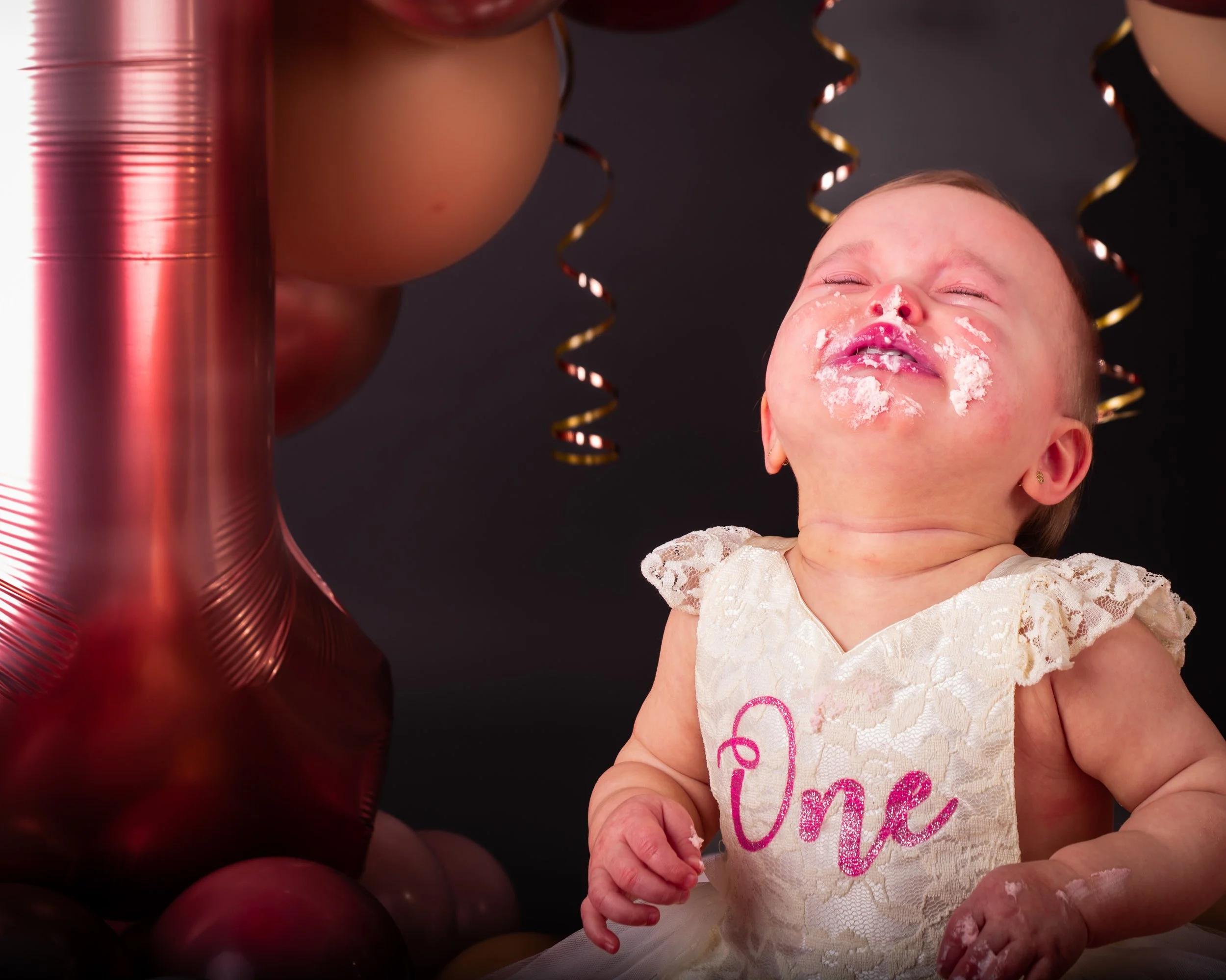 Een schattige baby met feestversiering, inclusief ballonnen en slingers, die vrolijk en blij is op haar eerste verjaardag.
